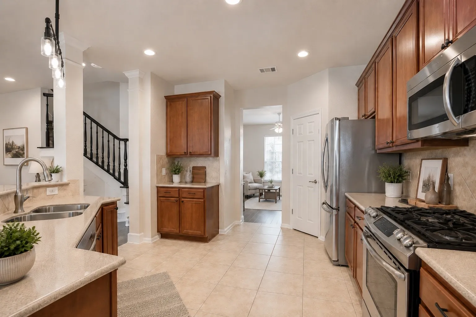 Kitchen featuring a double basin sink, stainless steel appliances, recessed lighting, wood-finish cabinetry, and neutral tile flooring