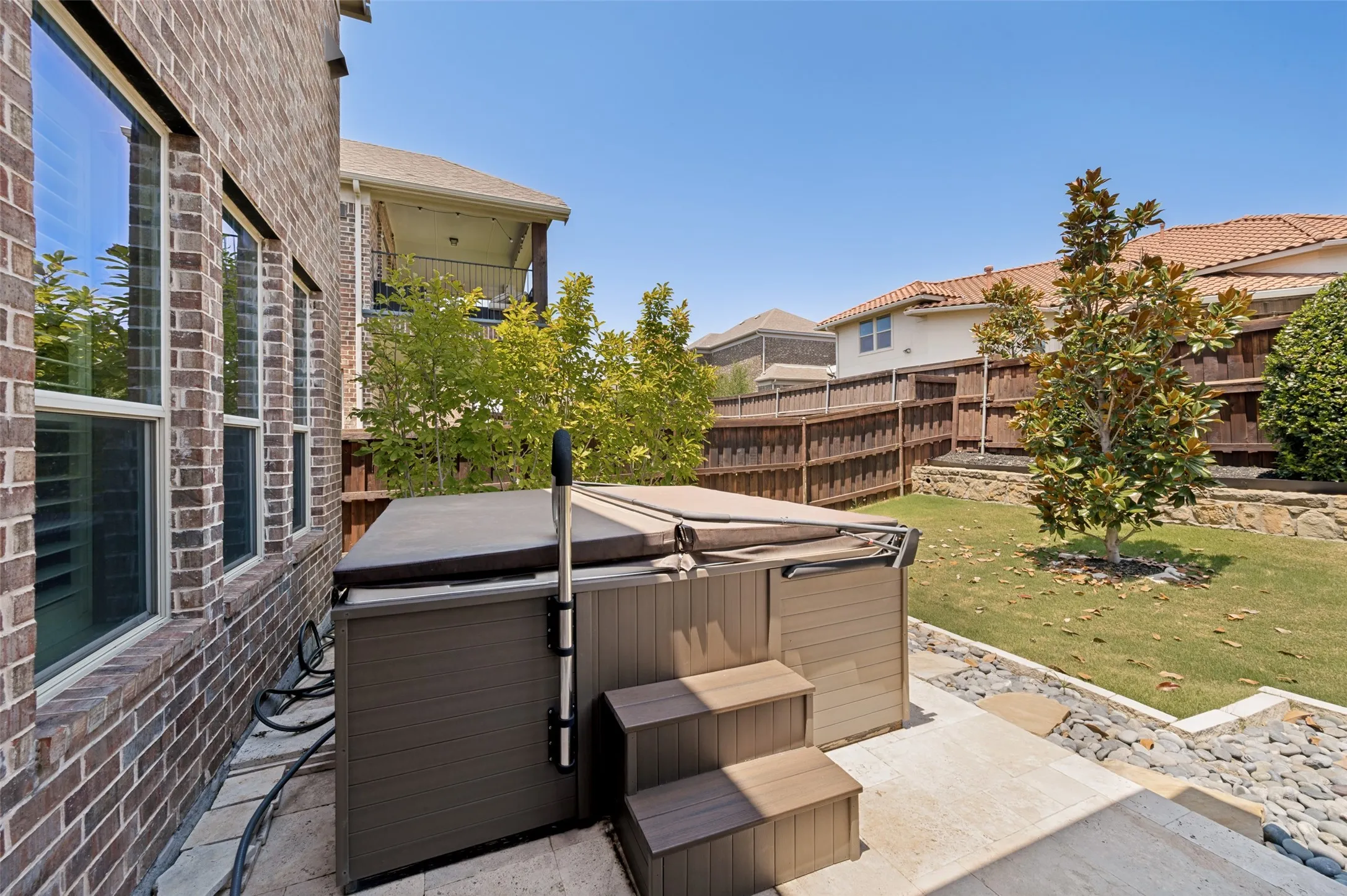 Backyard oasis featuring a spacious hot tub with integrated steps and dark composite surround, situated on a concrete patio