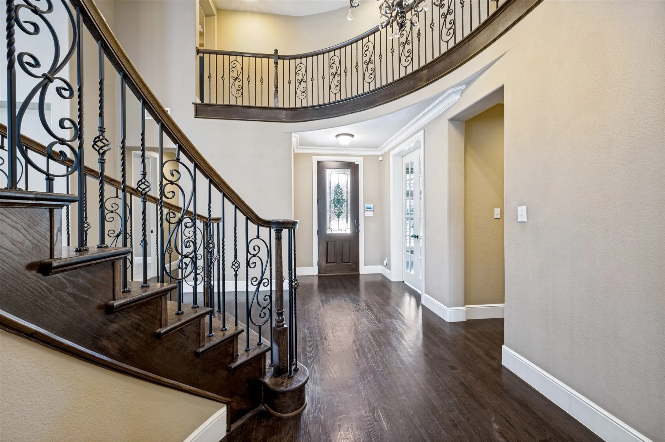 Grand entryway featuring a curved staircase with wrought iron balusters and wood-finish handrail