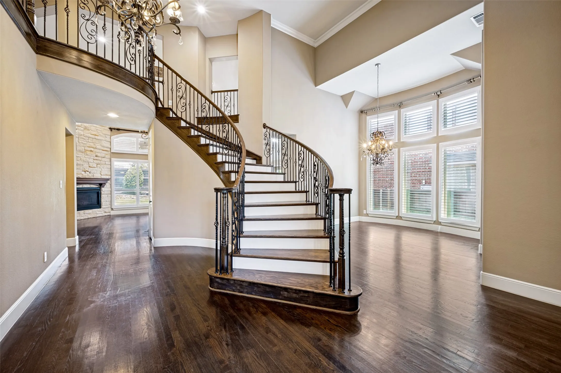 Grand entryway featuring a curved staircase with wrought iron balusters and dark wood treads