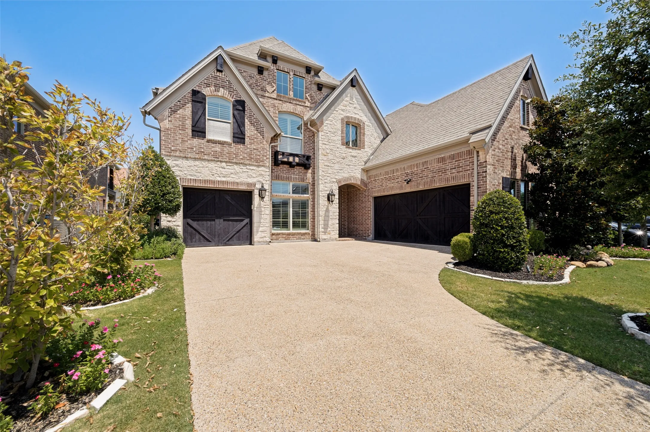 Two-story property featuring a brick and stone exterior, multiple gables, and a prominent arched entryway