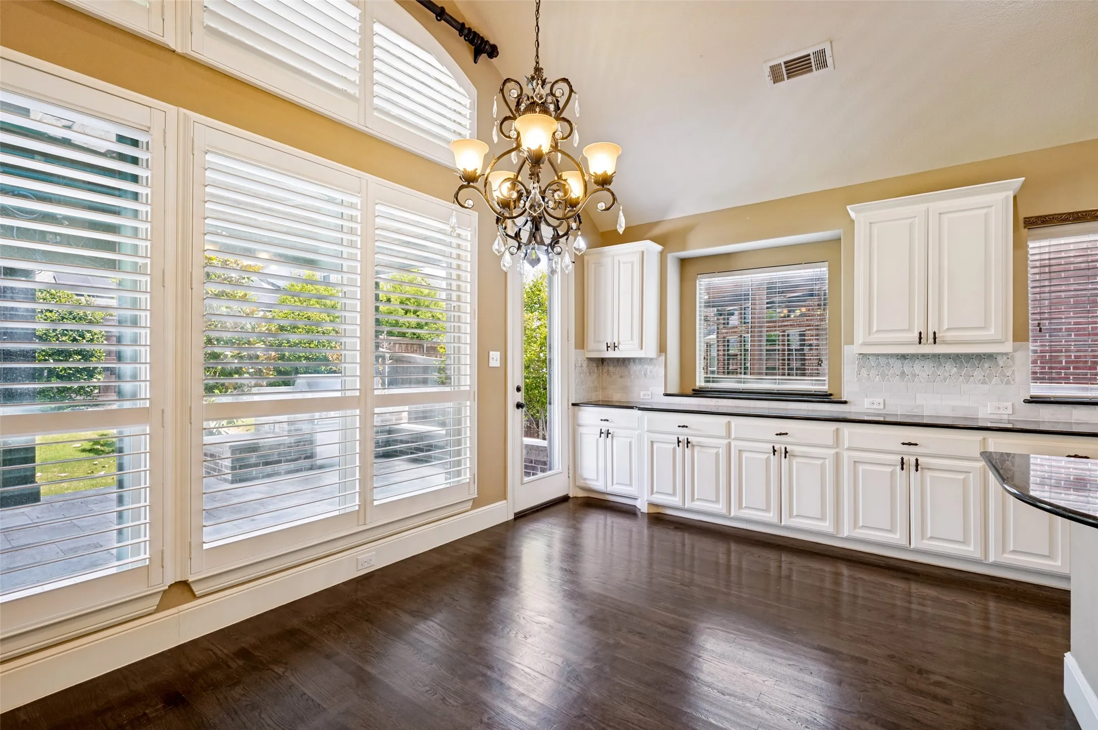 Spacious room featuring dark wood-finish flooring, white cabinetry with dark hardware, and dark countertops
