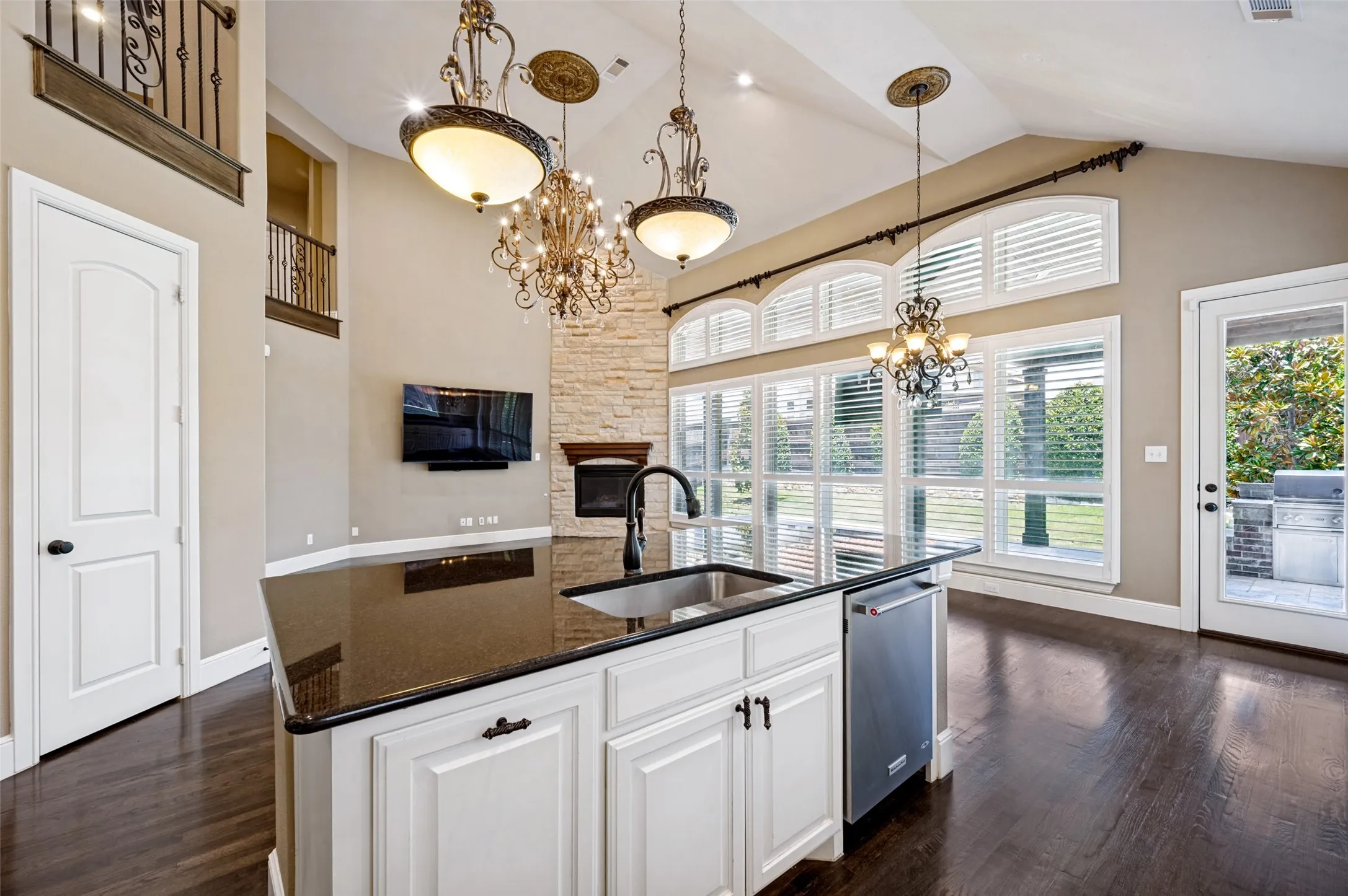 Kitchen island featuring white cabinetry, a dark countertop, and a built-in sink with a gooseneck faucet