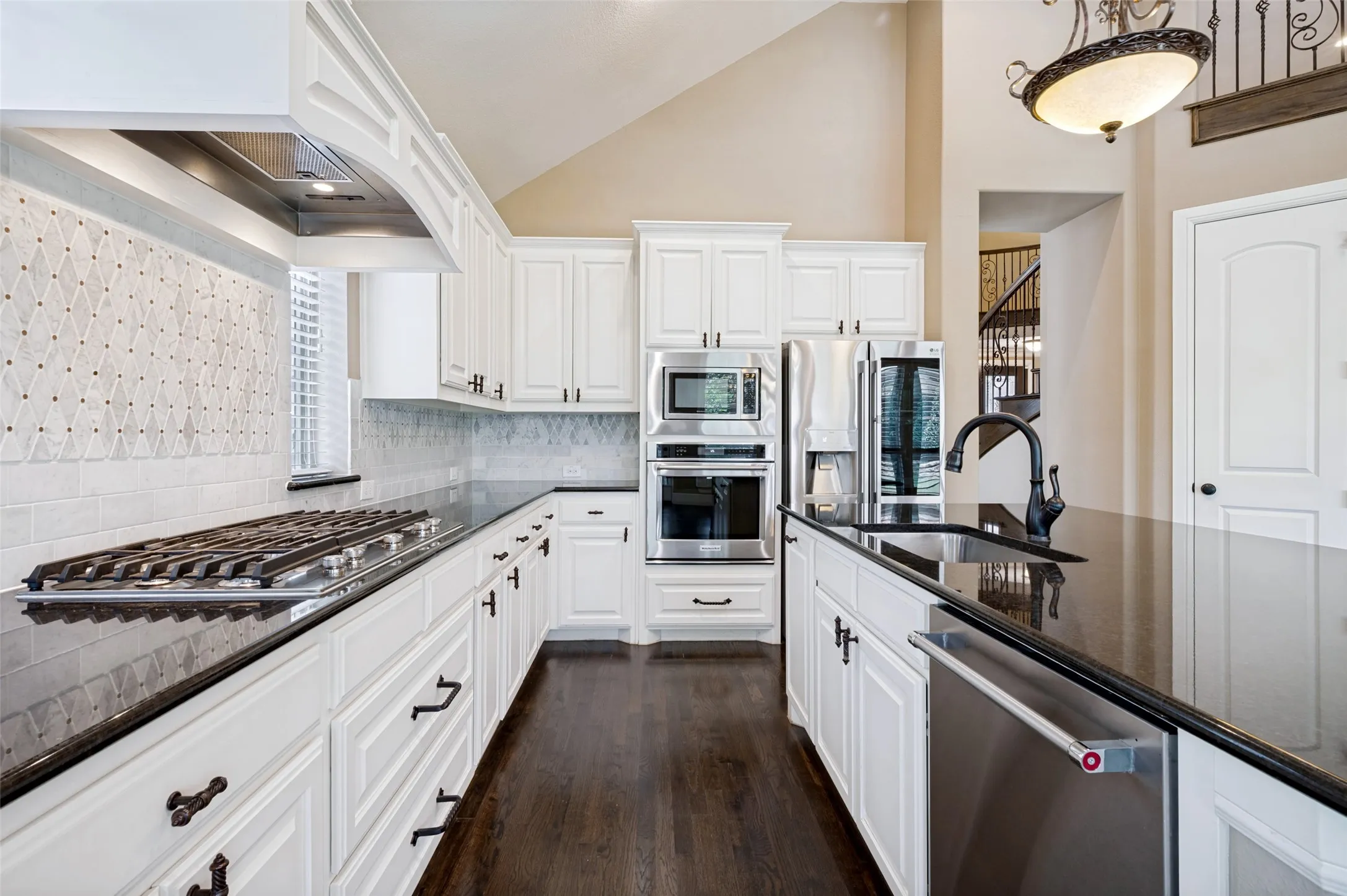 Gourmet kitchen featuring white cabinetry, dark stone countertops, stainless steel appliances, a gas range, and a decorative tile backsplash