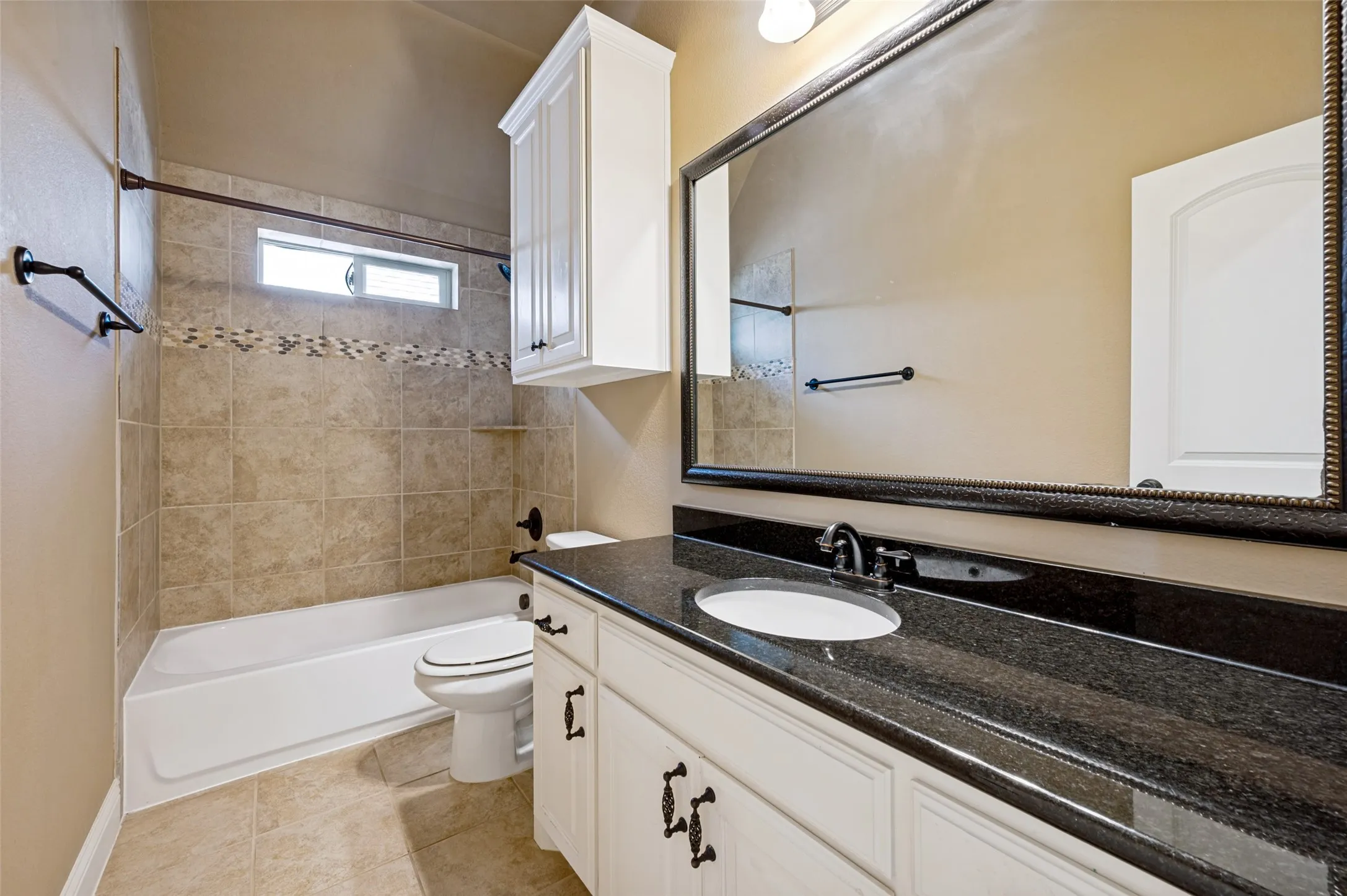 Spa-inspired master bathroom featuring a white vanity with dual-sink configuration, black granite countertop, and an oversized framed mirror