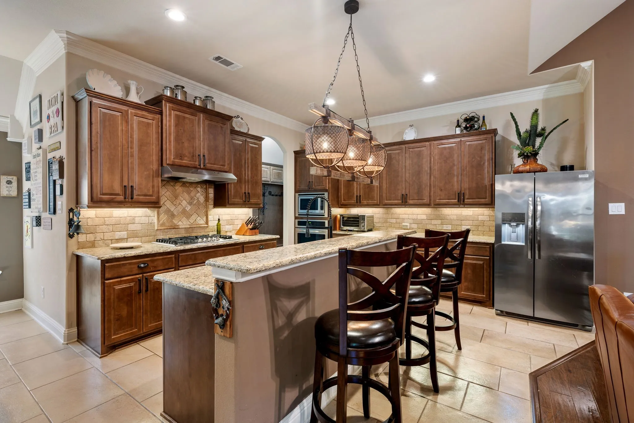Kitchen featuring wood cabinetry, light-toned backsplash, stainless steel appliances, a gas range, and a breakfast bar with stone countertops