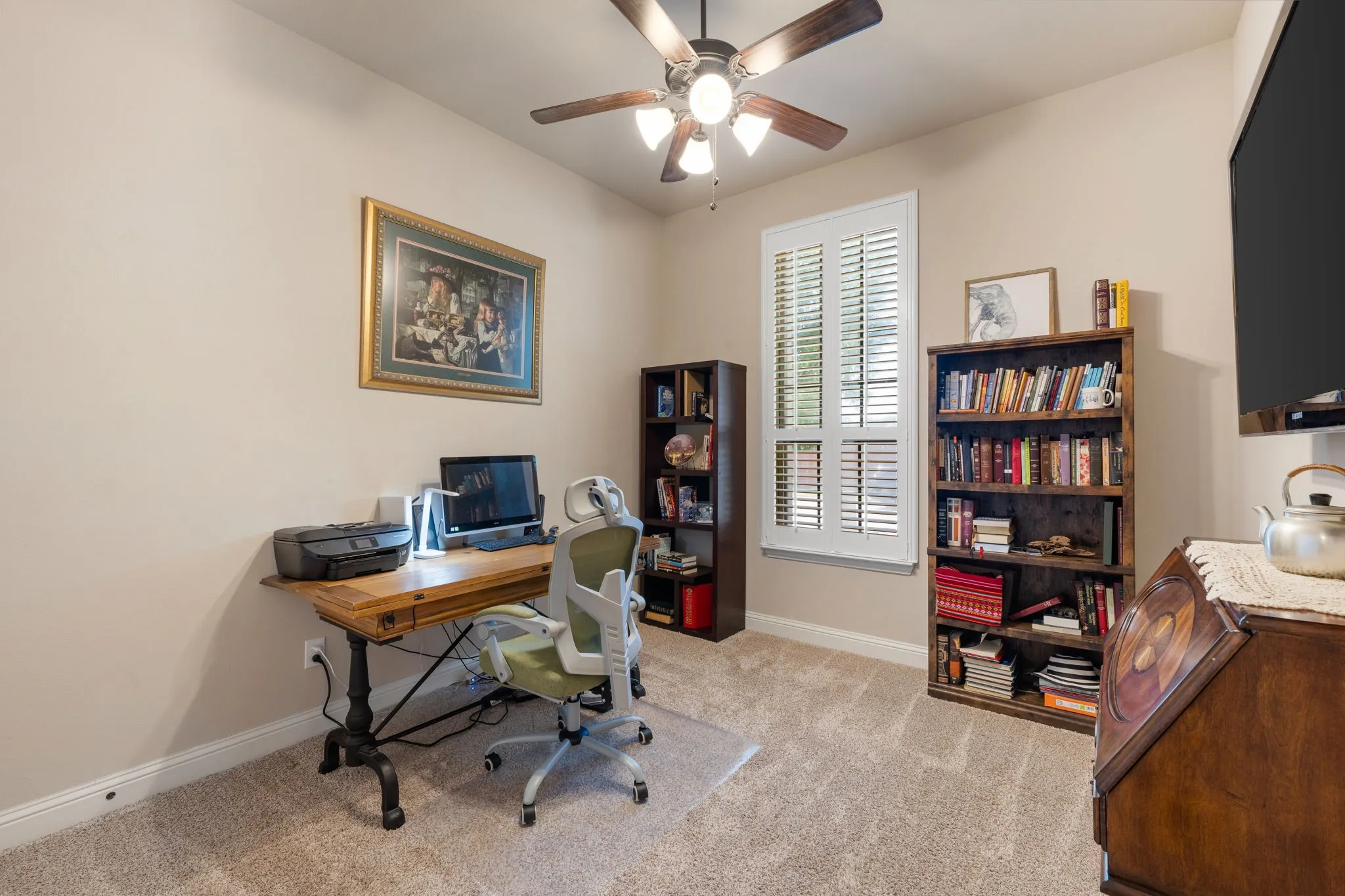 Secondary bedroom Carpeted room featuring a ceiling fan with integrated lighting, a window with plantation shutters, and light-toned wall paint