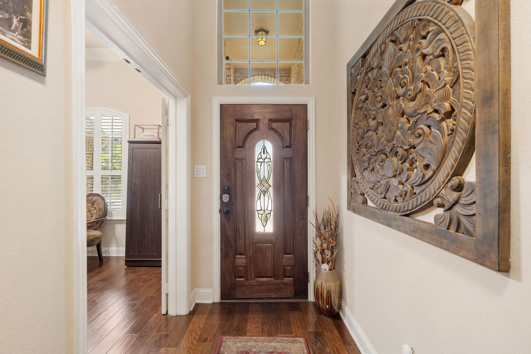 Entryway featuring a dark wood-finish door with decorative glass inlay, transom window, and wood-finish flooring