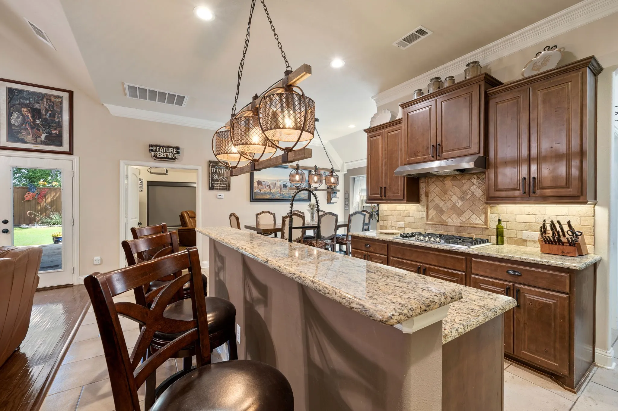 Kitchen featuring a granite countertop island, rich wood cabinetry, tile backsplash with a herringbone pattern, stainless steel gas range, and recessed lighting