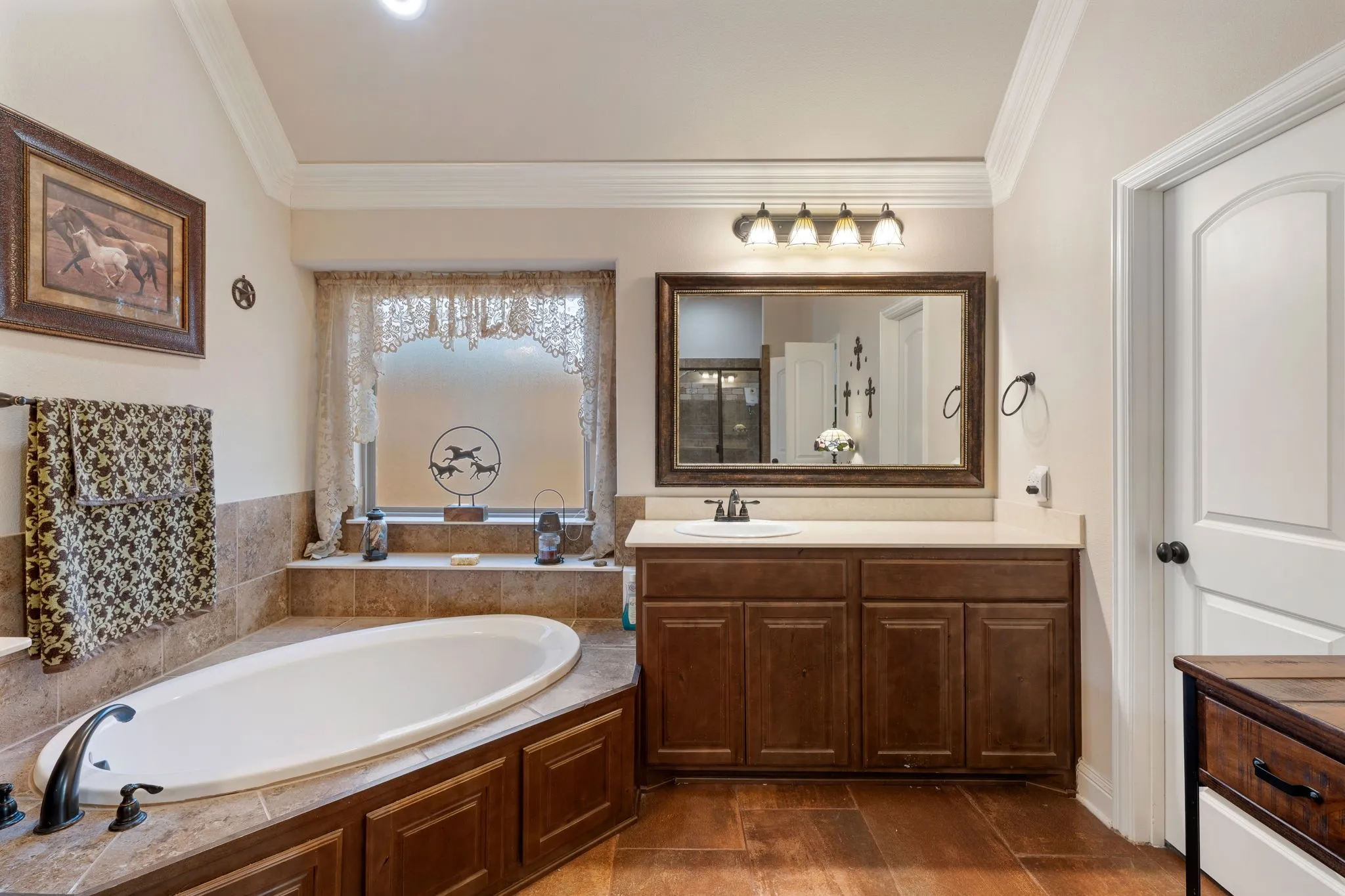 Soaking tub with bronze fixtures, surrounded by a tiled deck and wood-finish paneling
