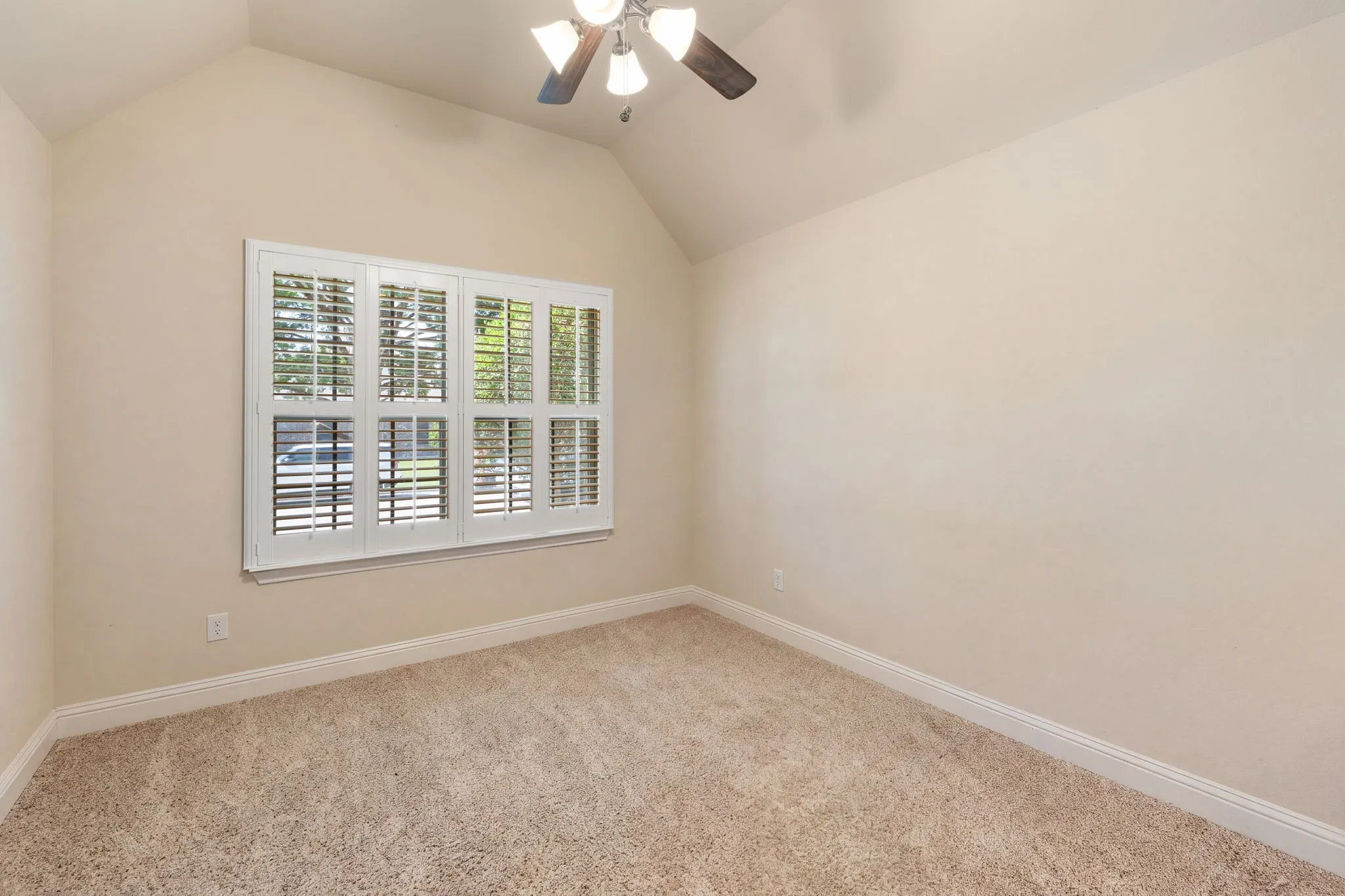 Secondary bedroom Vaulted ceiling room with plantation-shutter window, carpet flooring, base molding, and ceiling fan with light fixture