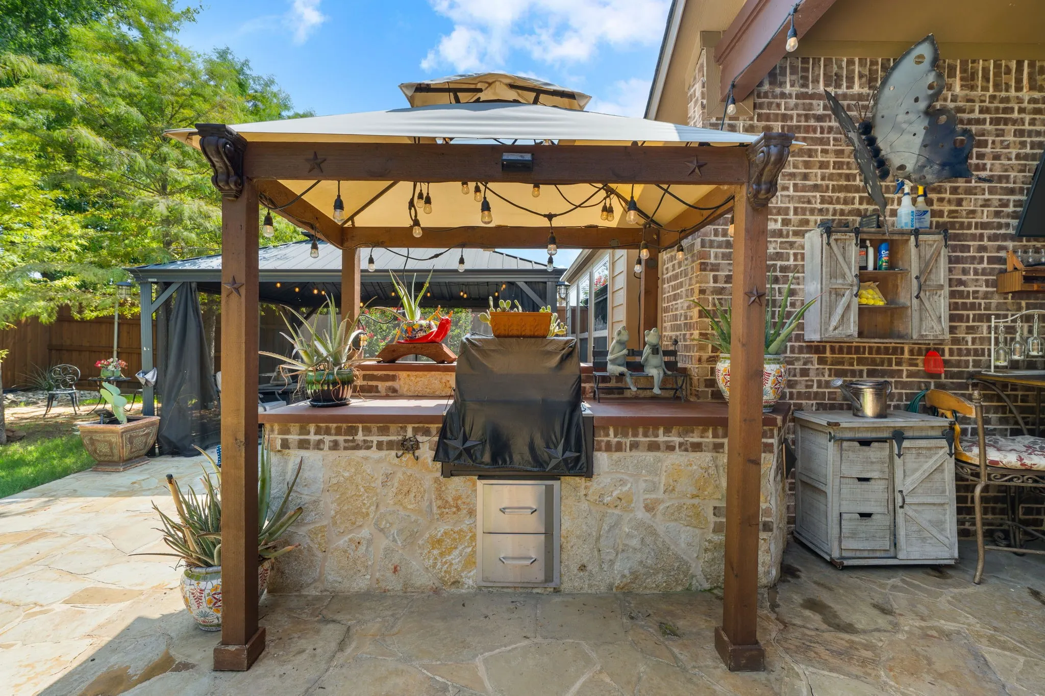 Outdoor kitchen featuring a stone and brick base, wood-finish countertop, and built-in grill