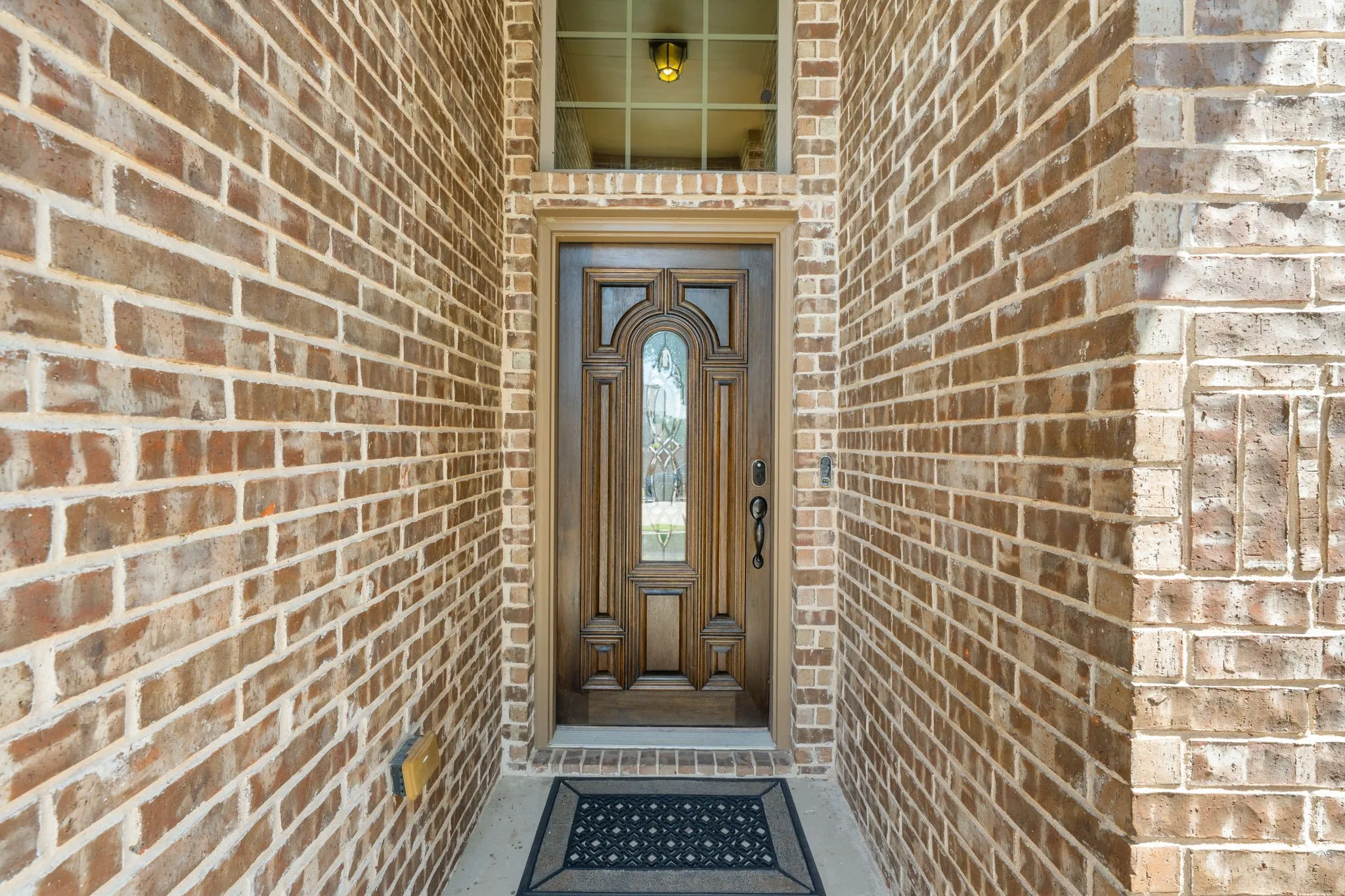 Solid brick exterior with a substantial wooden front door featuring decorative carving and a central glass panel