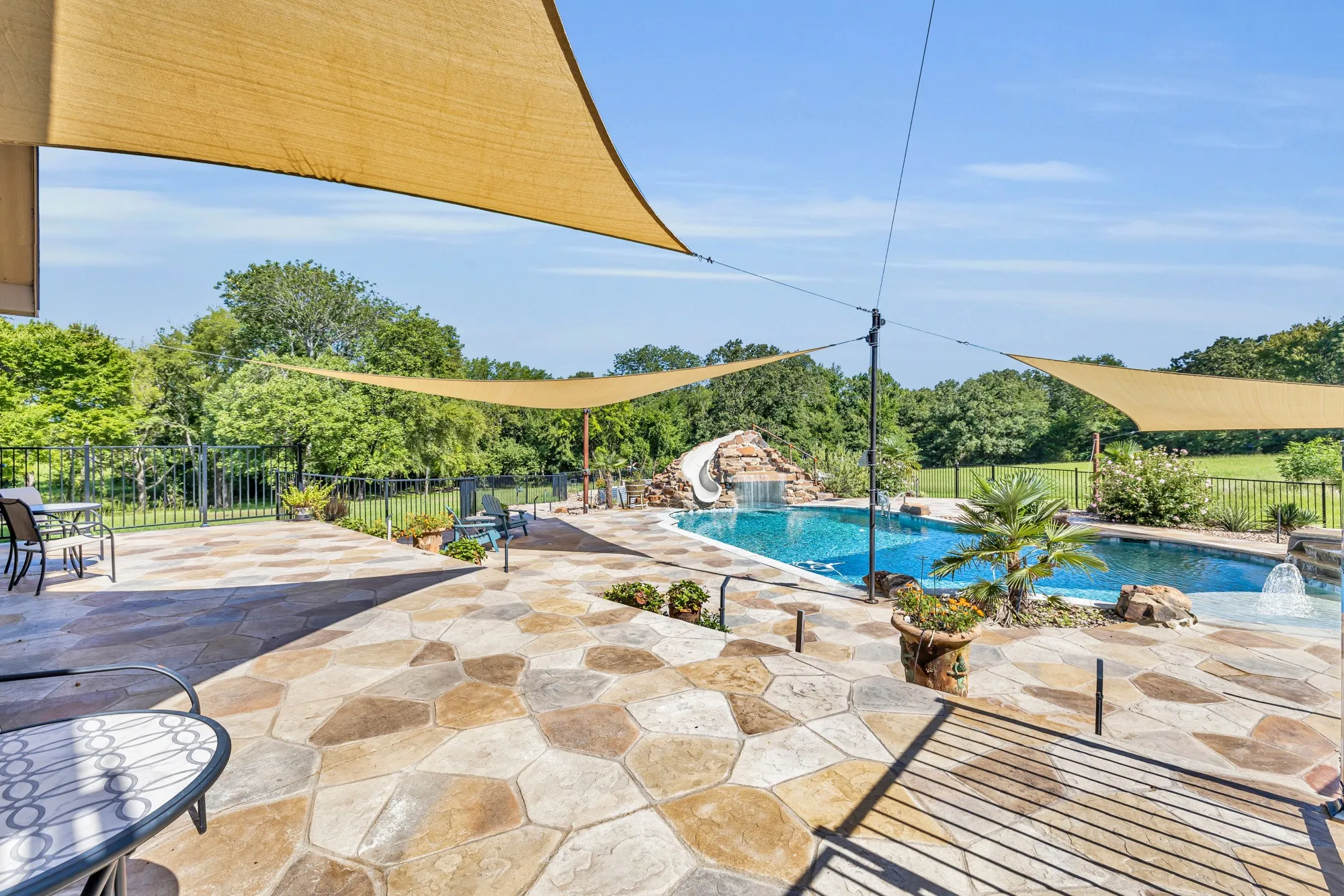 Expansive outdoor living area featuring a freeform pool, a built-in rock slide with waterfall, and a separate spa with a waterfall feature