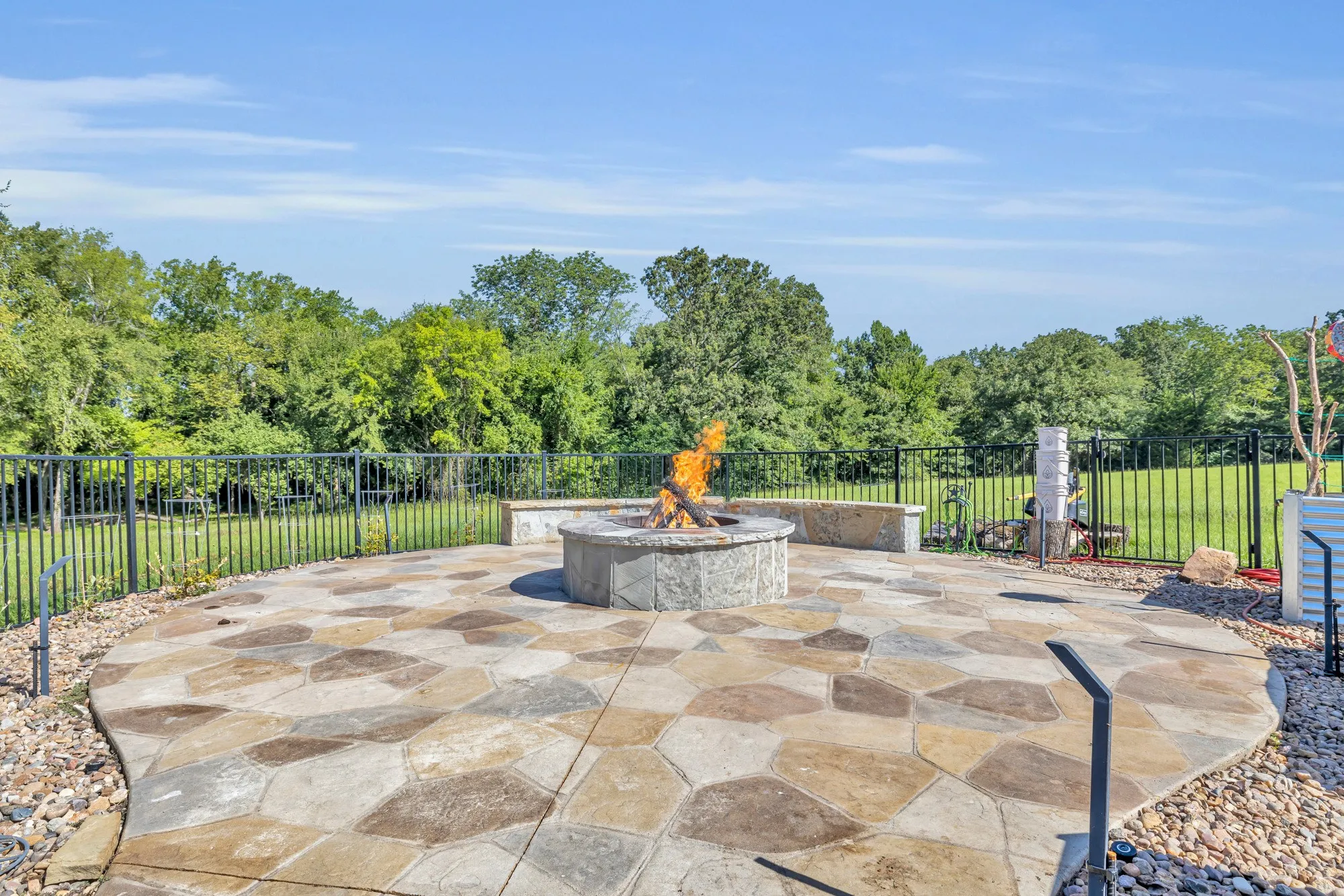 Expansive patio featuring a stone fire pit, irregular flagstone pattern, and a stone retaining wall