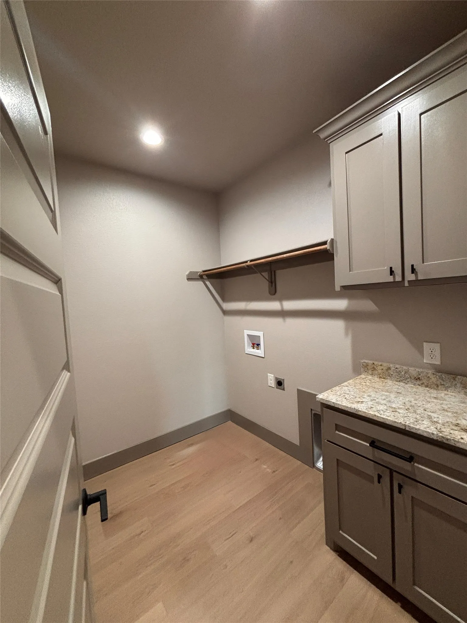 Utility room featuring wood-finish flooring, recessed lighting, and a built-in shelf