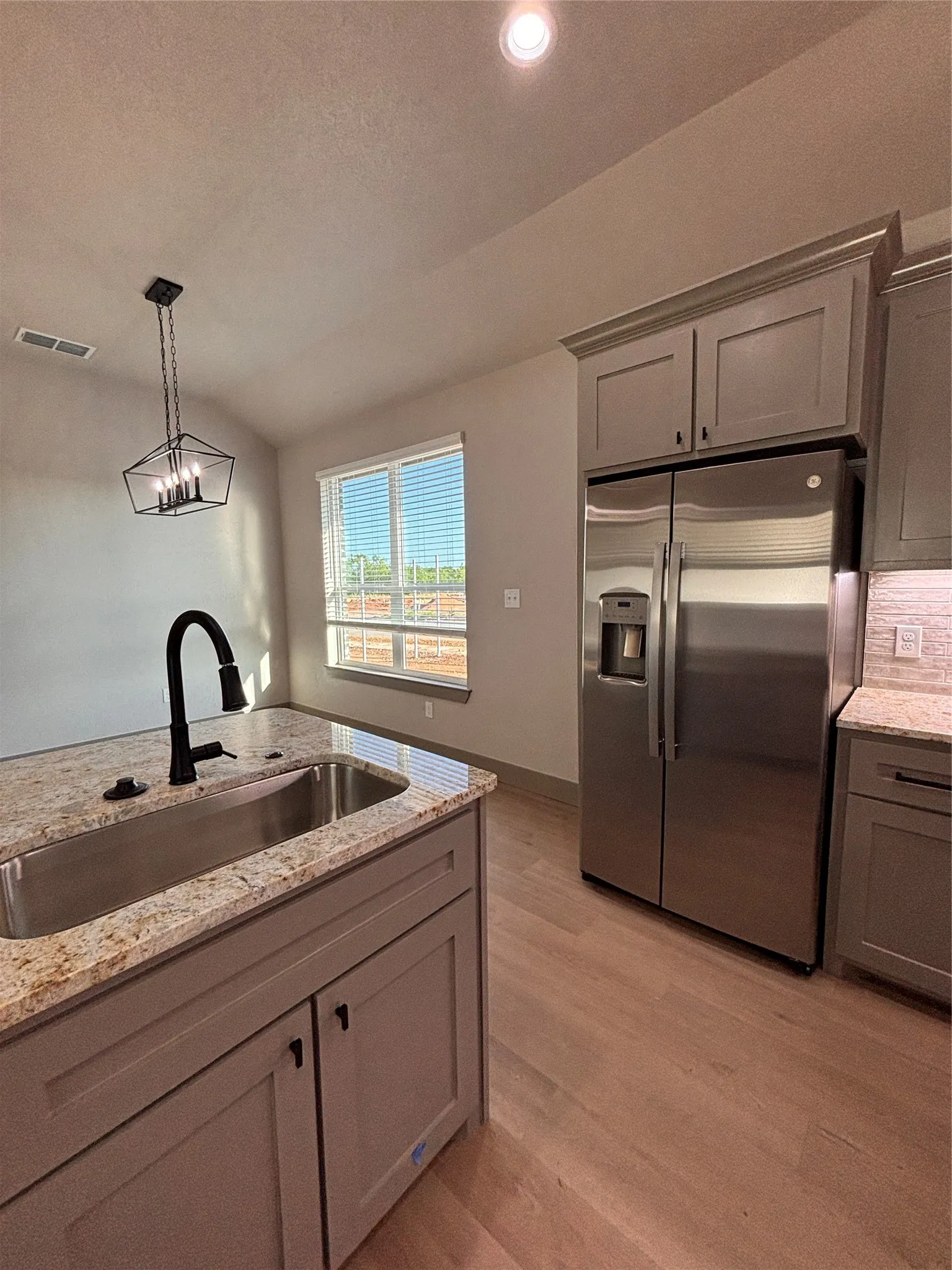 Kitchen featuring light wood-finish flooring, stainless steel appliances, granite countertops, and gray cabinetry