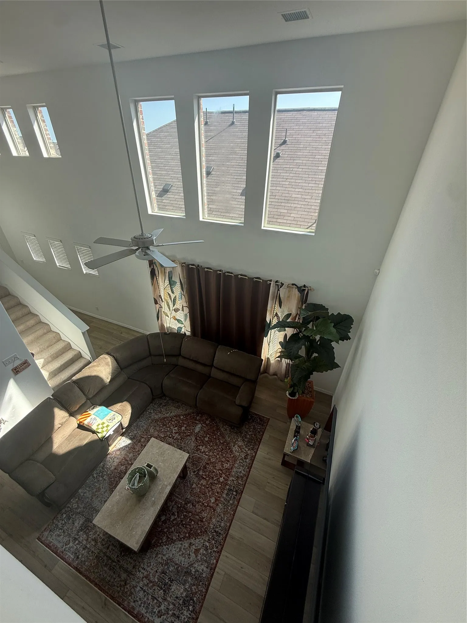 Open-concept living area featuring a high ceiling, a ceiling fan, and multiple wall-mounted windows