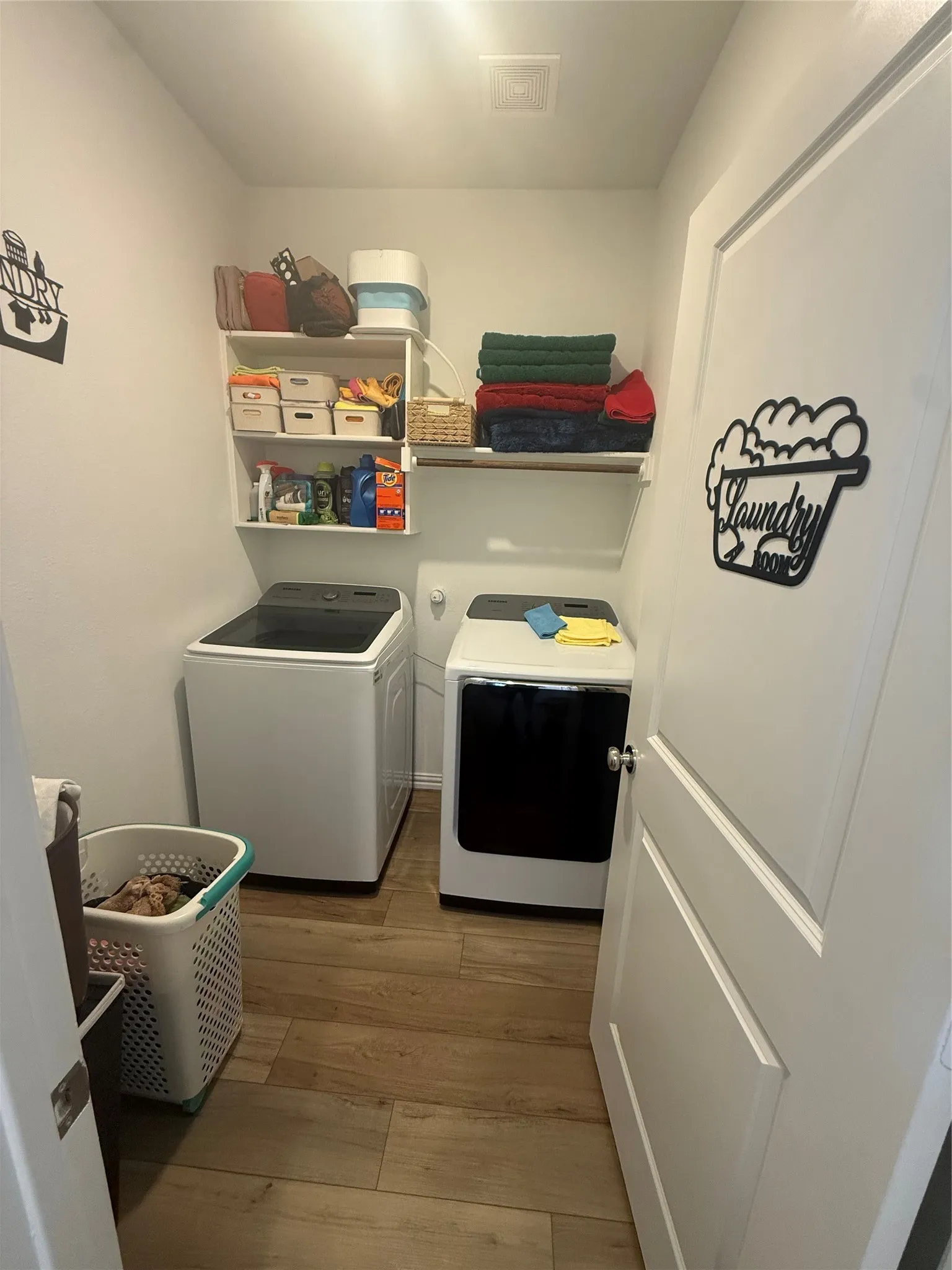Dedicated utility space featuring wood-finish flooring, white walls, and built-in shelving