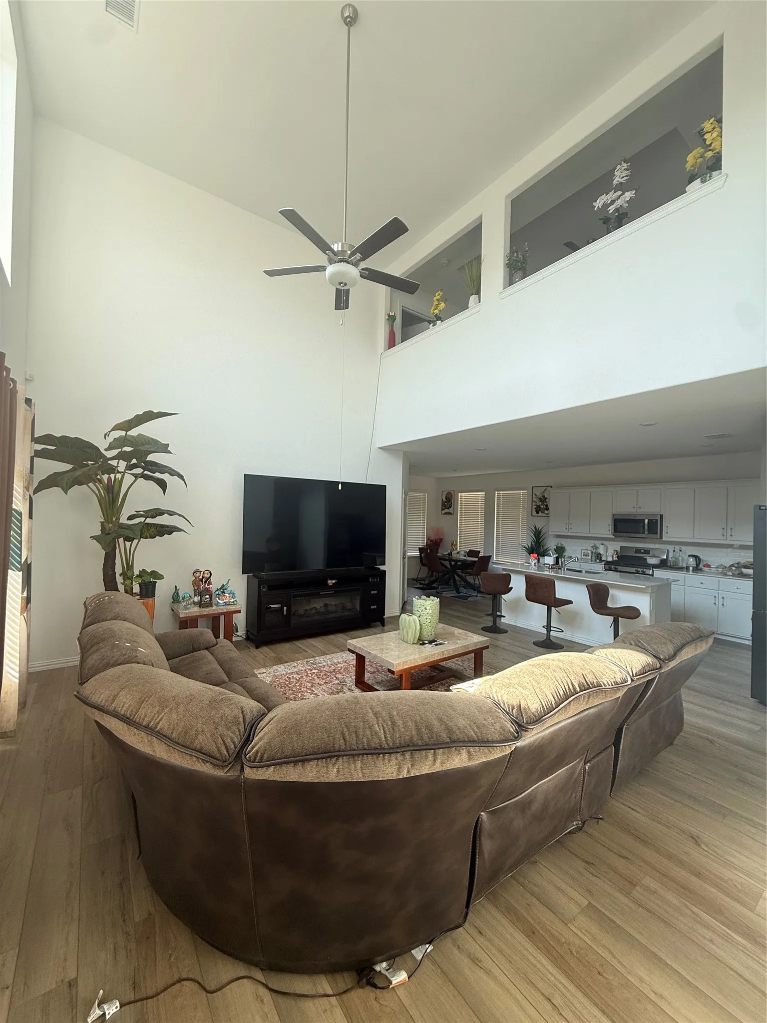 Two-story living area featuring wood-finish flooring, a ceiling fan, and an open concept layout