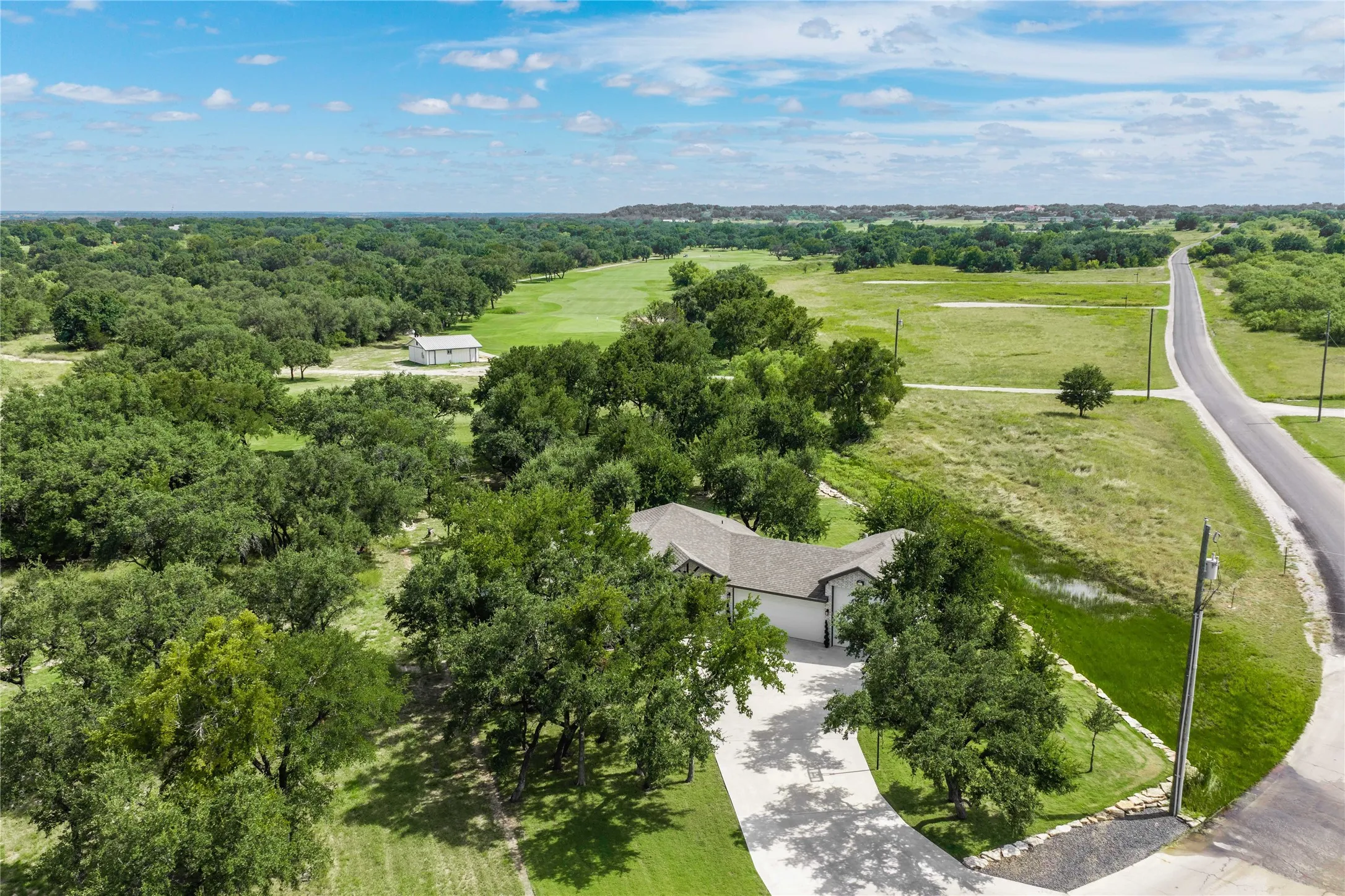Ranch-style residence featuring an attached two-car garage, an expansive driveway, and a mature tree canopy