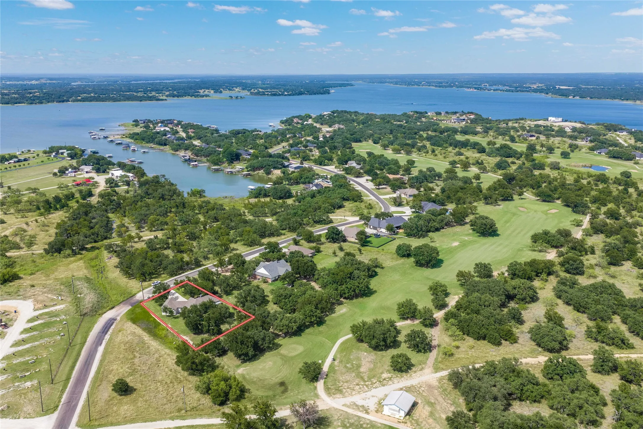 Aerial perspective showcasing a single-story residence within a tree-lined lot, bordering a golf course