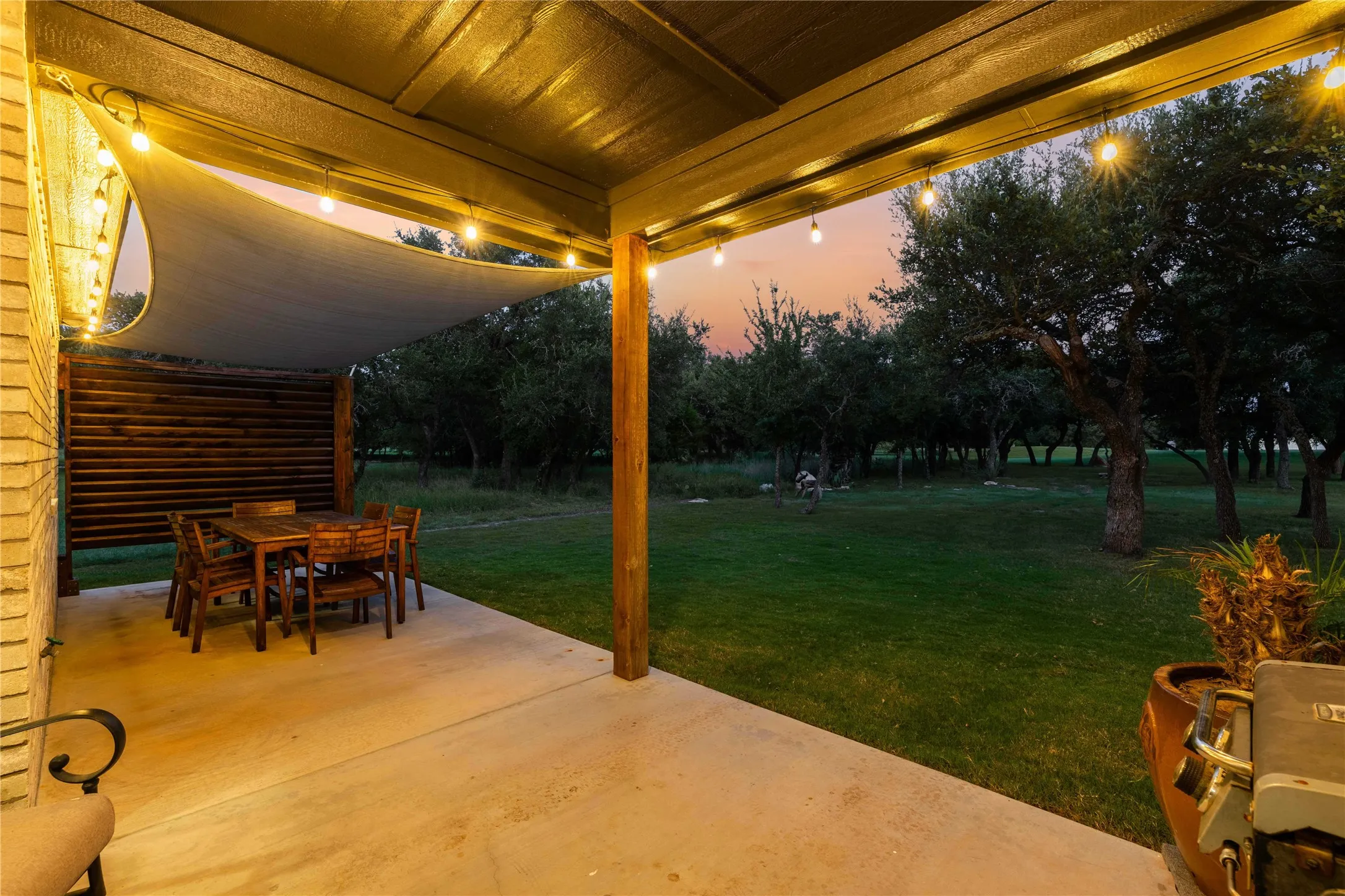 Covered patio featuring a concrete slab, string lighting, and a shade sail