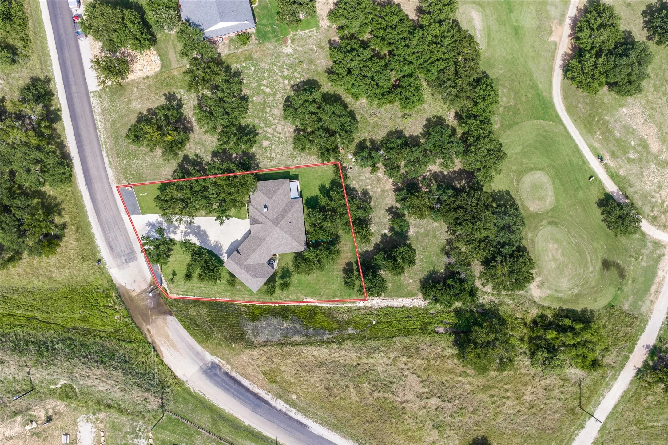 Aerial perspective showcasing the property's expansive lot, mature trees, and proximity to a golf course