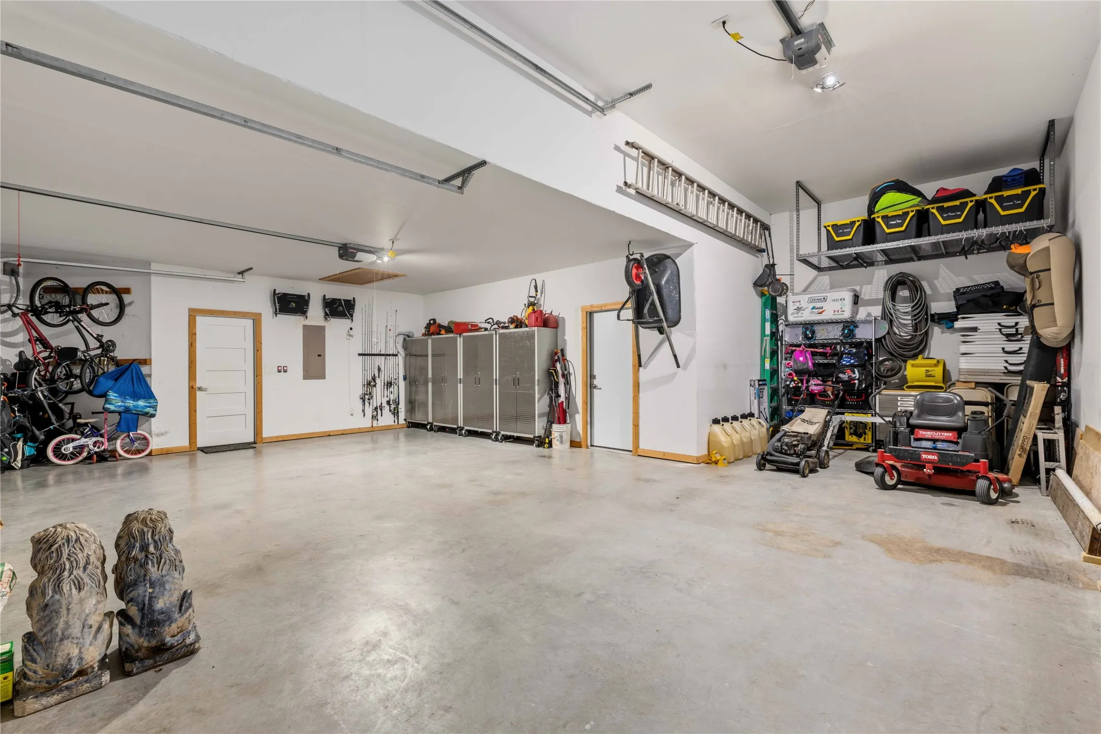 Spacious garage with light-toned concrete flooring, white walls, and exposed ceiling joists