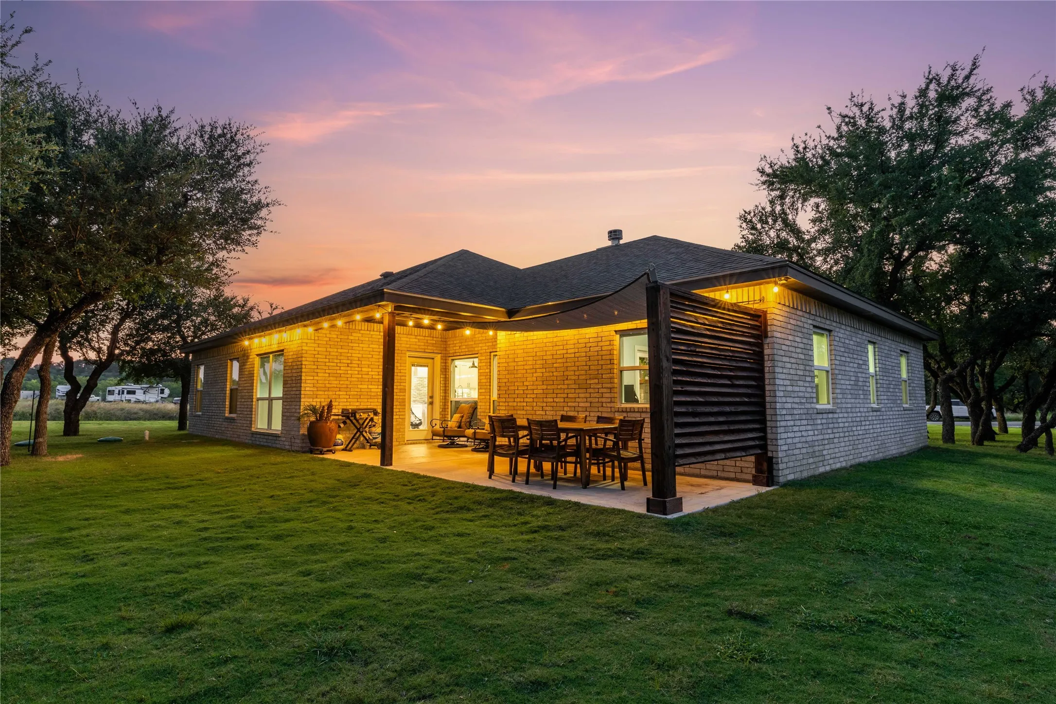 Expansive backyard with a covered patio area, brick exterior, and a privacy screen