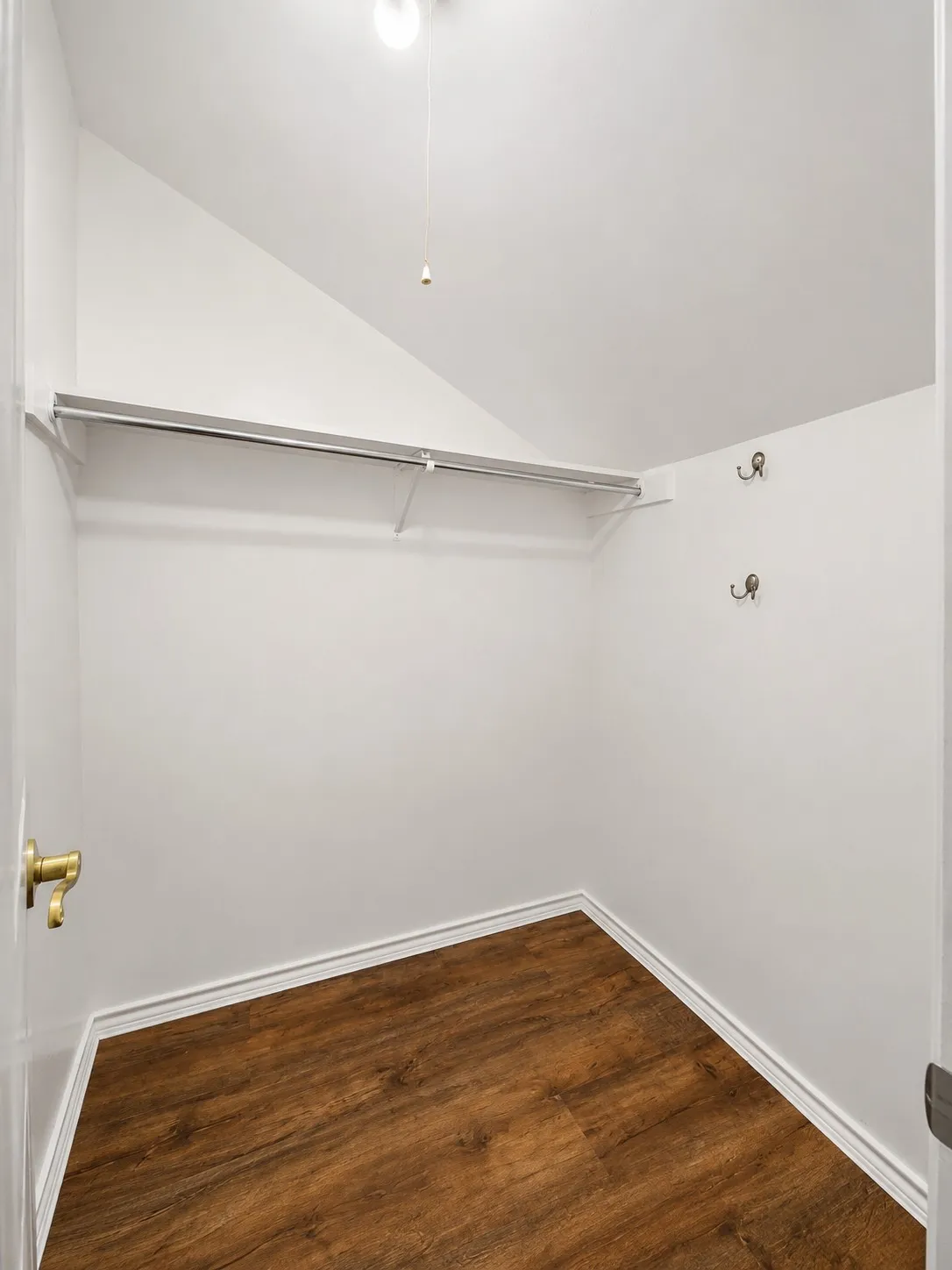 Sloped ceiling, wood-finish flooring, integrated shelving, and wall-mounted hooks