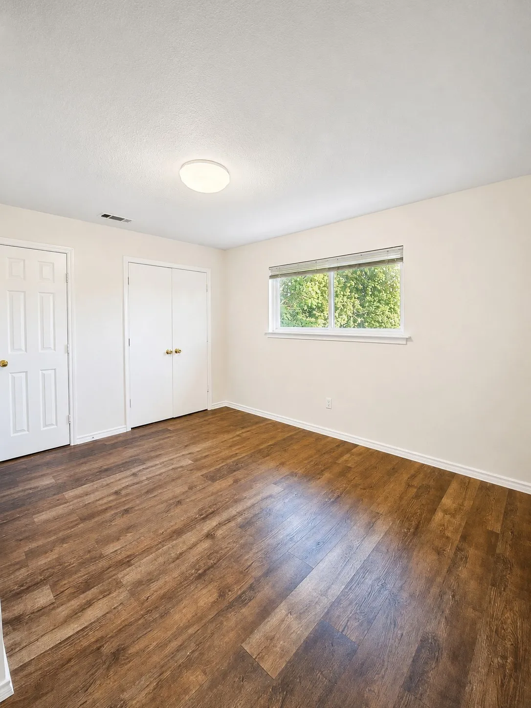 Recessed window with blinds, wood-finish flooring, and white trim