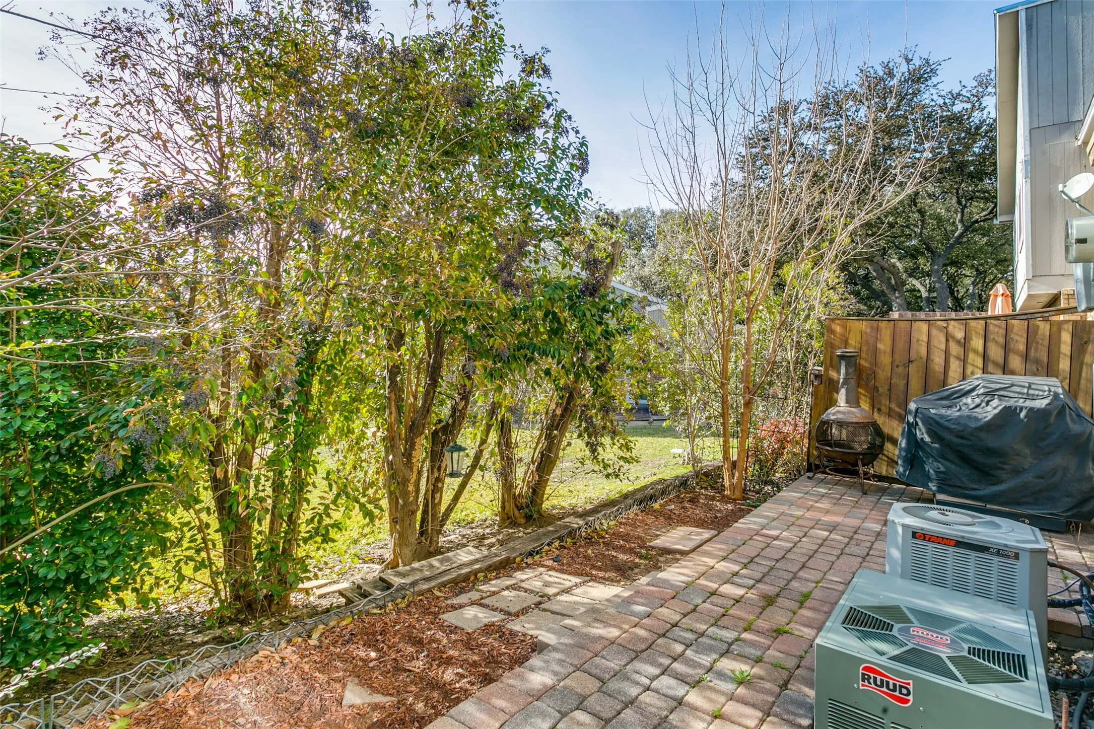 Paved patio area featuring brick pavers and a wooden privacy fence