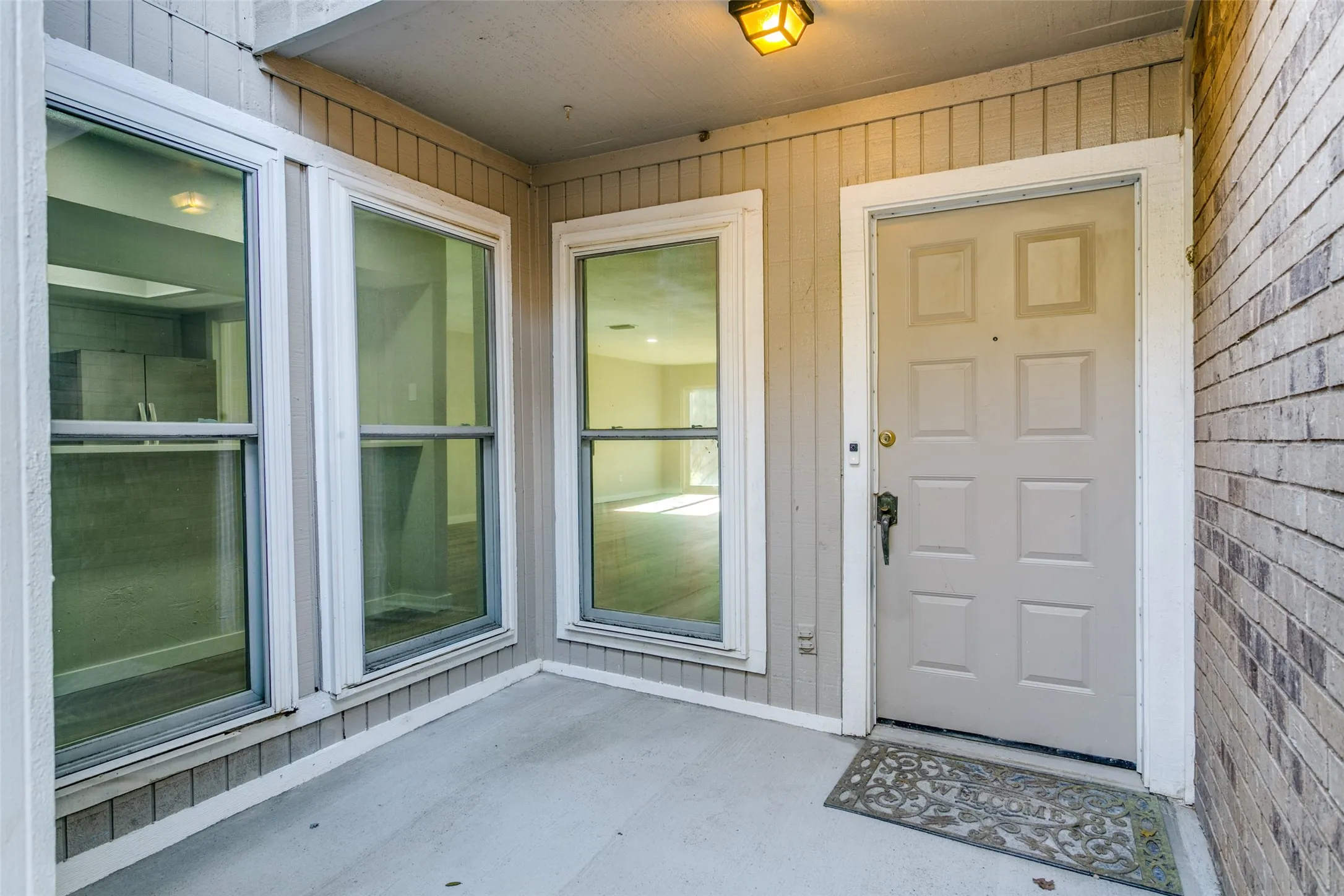 Inviting front entry featuring a paneled door, exterior wall lantern, and brick and siding facade
