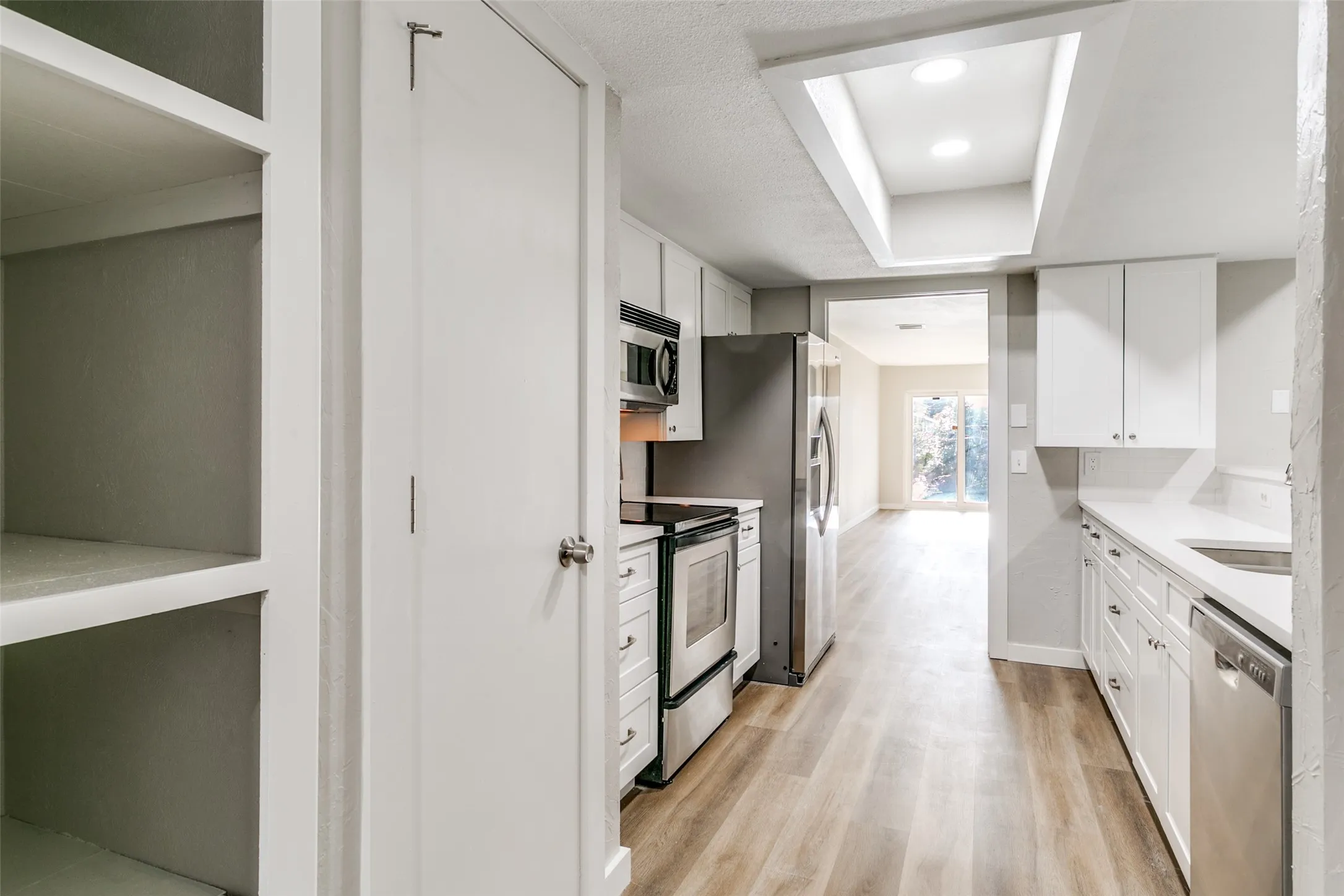 Bright kitchen featuring wood-finish flooring and white cabinetry