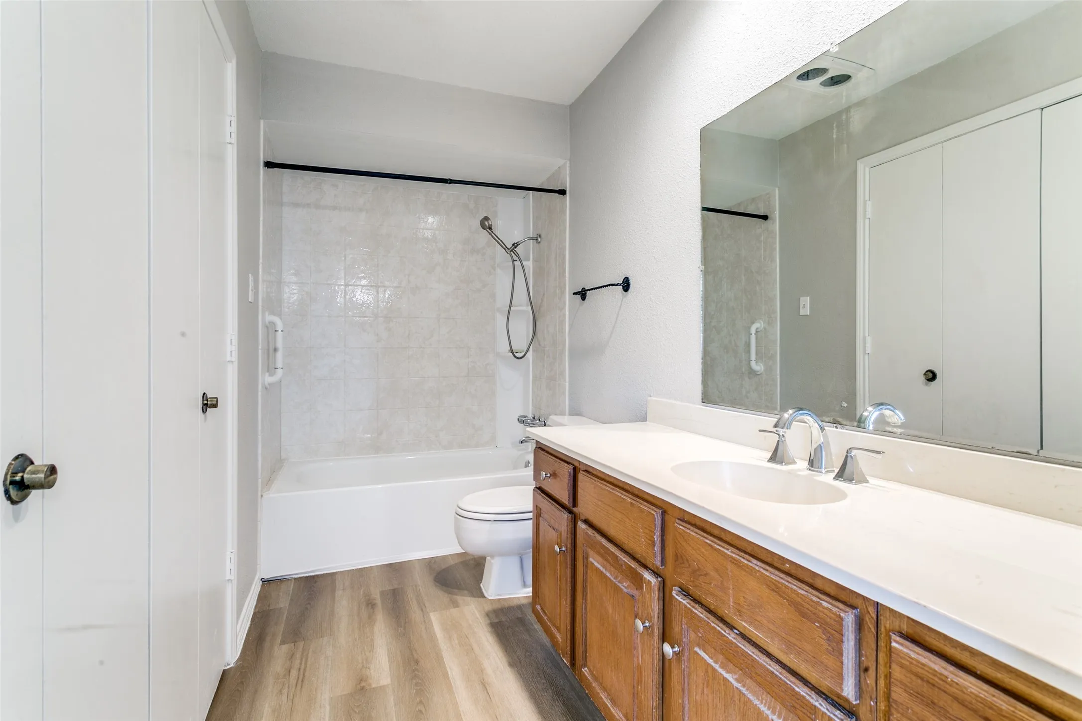 Bathroom featuring a dual-sink vanity with a light-toned countertop, wood-finish cabinetry, and chrome fixtures