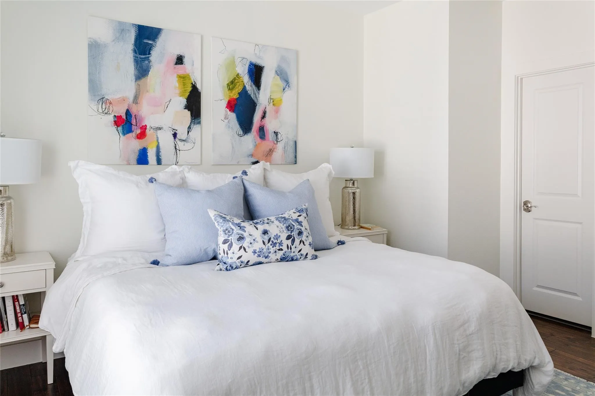 Bedroom featuring wood-finish flooring, a white paneled door with brushed nickel hardware, and neutral wall paint