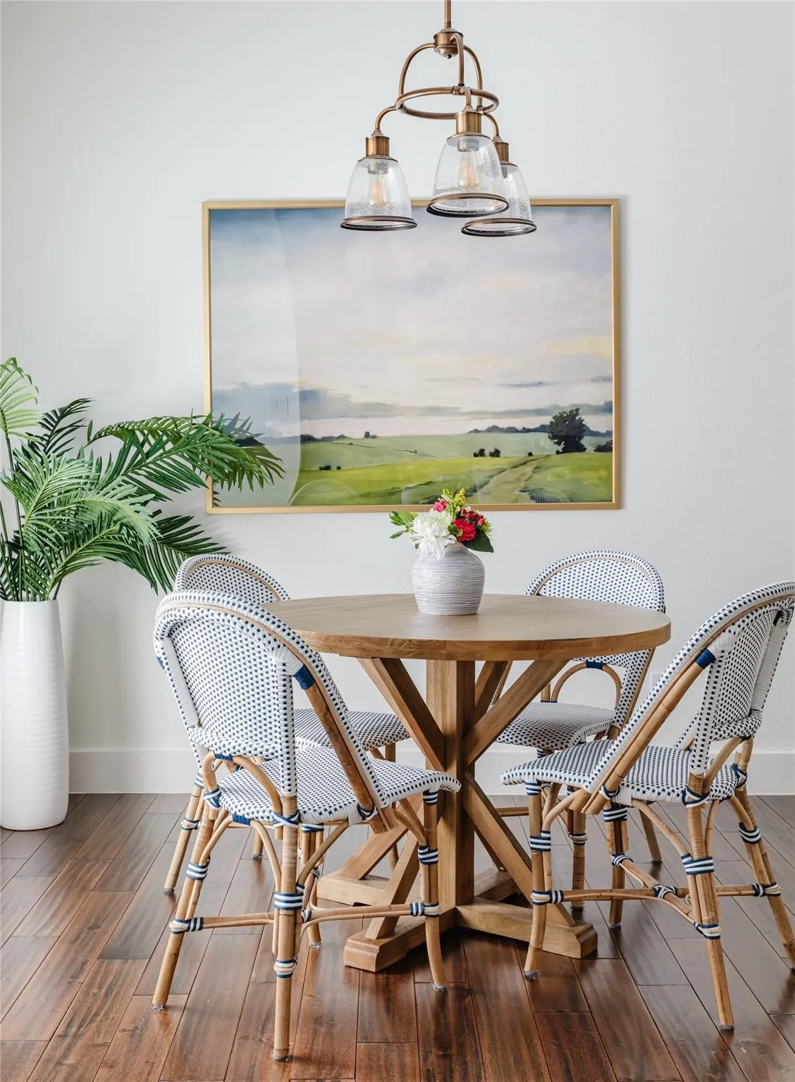 Hardwood-finish flooring grounding a dining area featuring a bronze-finish chandelier with bell-shaped glass shades
