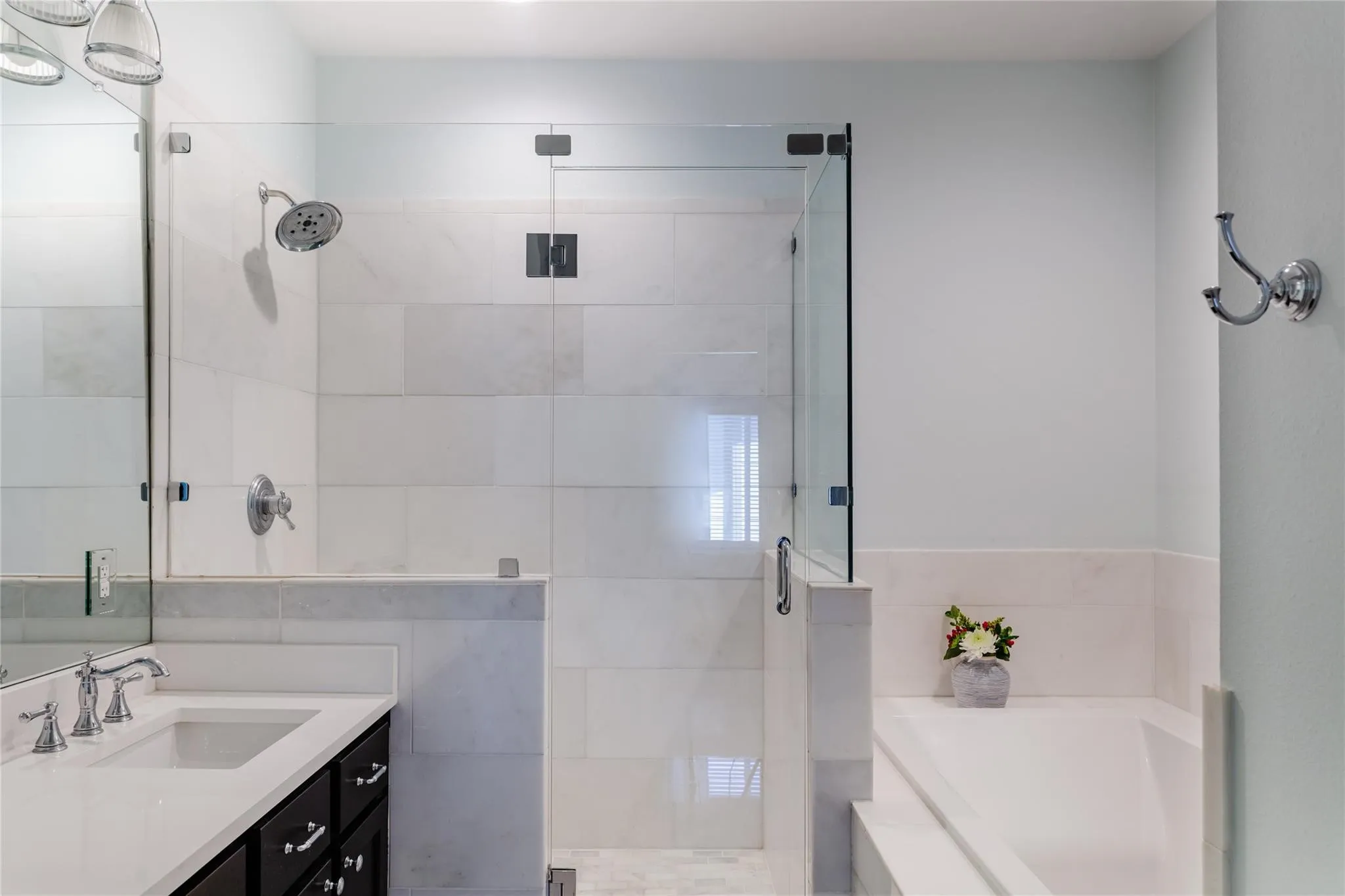Shower with frameless glass enclosure, white rectangular wall tiles, and chrome shower fixtures