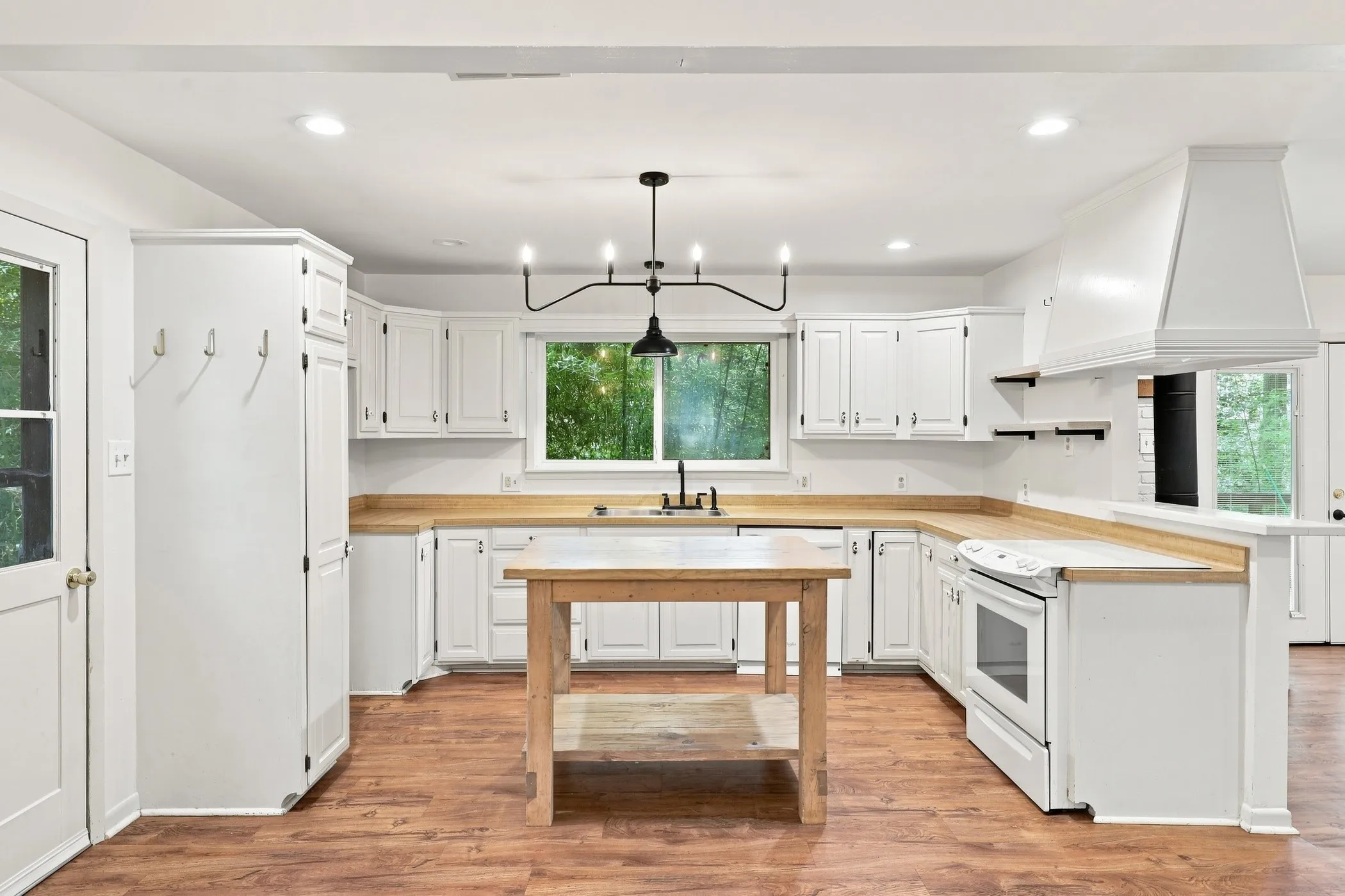 Spacious kitchen featuring white cabinetry, light wood-finish countertops, stainless steel appliances, and wood-finish flooring