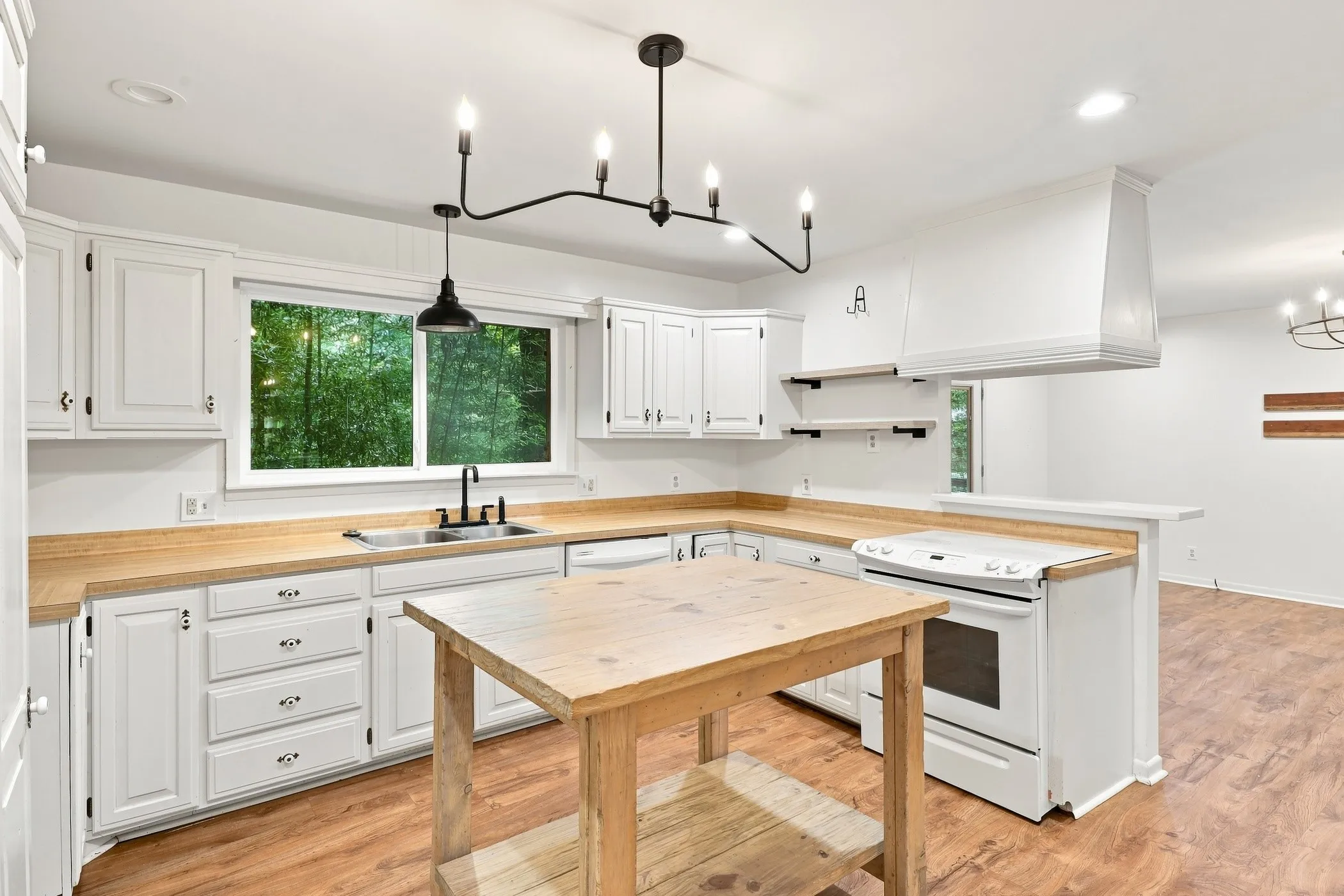 White kitchen cabinetry with wood-finish countertops, stainless steel sink, and black faucet