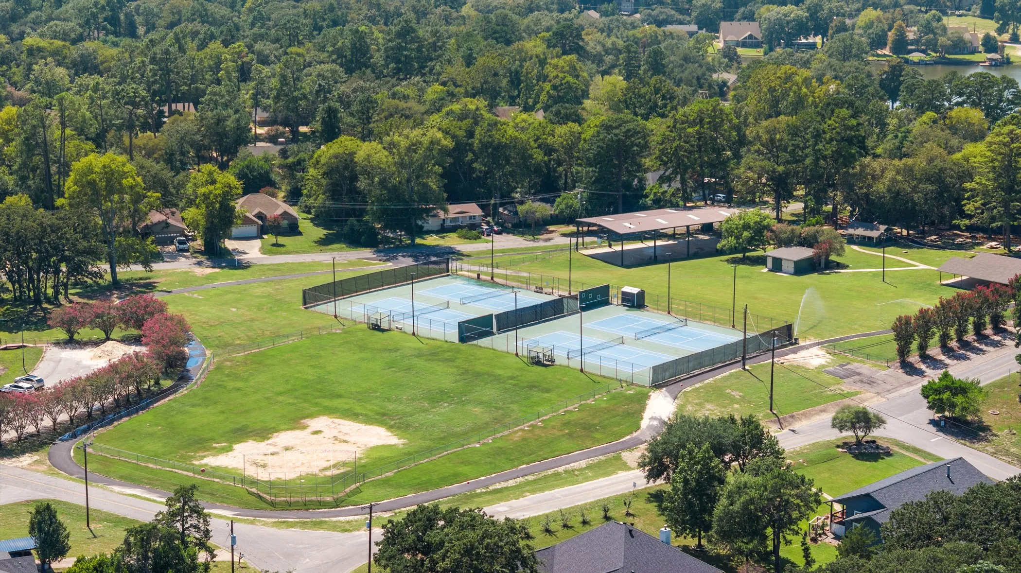 Expansive recreational grounds featuring four tennis courts, an open-air pavilion, and a separate utility building