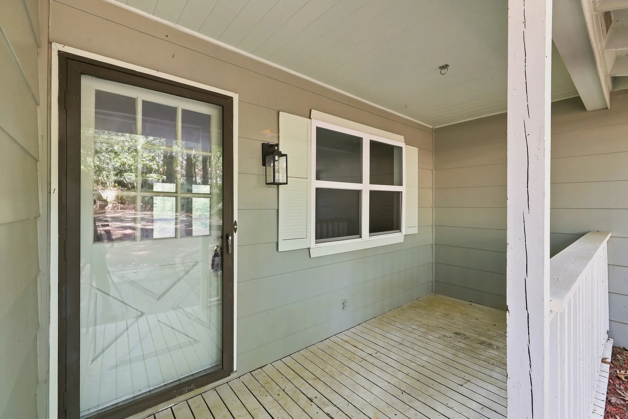 Covered porch featuring a full-light storm door, decorative wall sconce, and horizontal siding