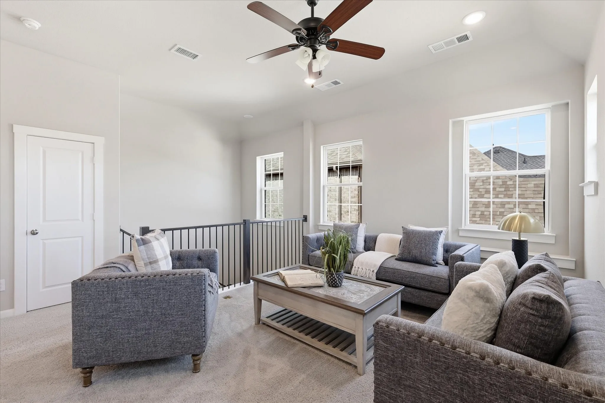 Vaulted ceiling with a ceiling fan, recessed lighting, carpet flooring, multiple windows, and a black iron railing