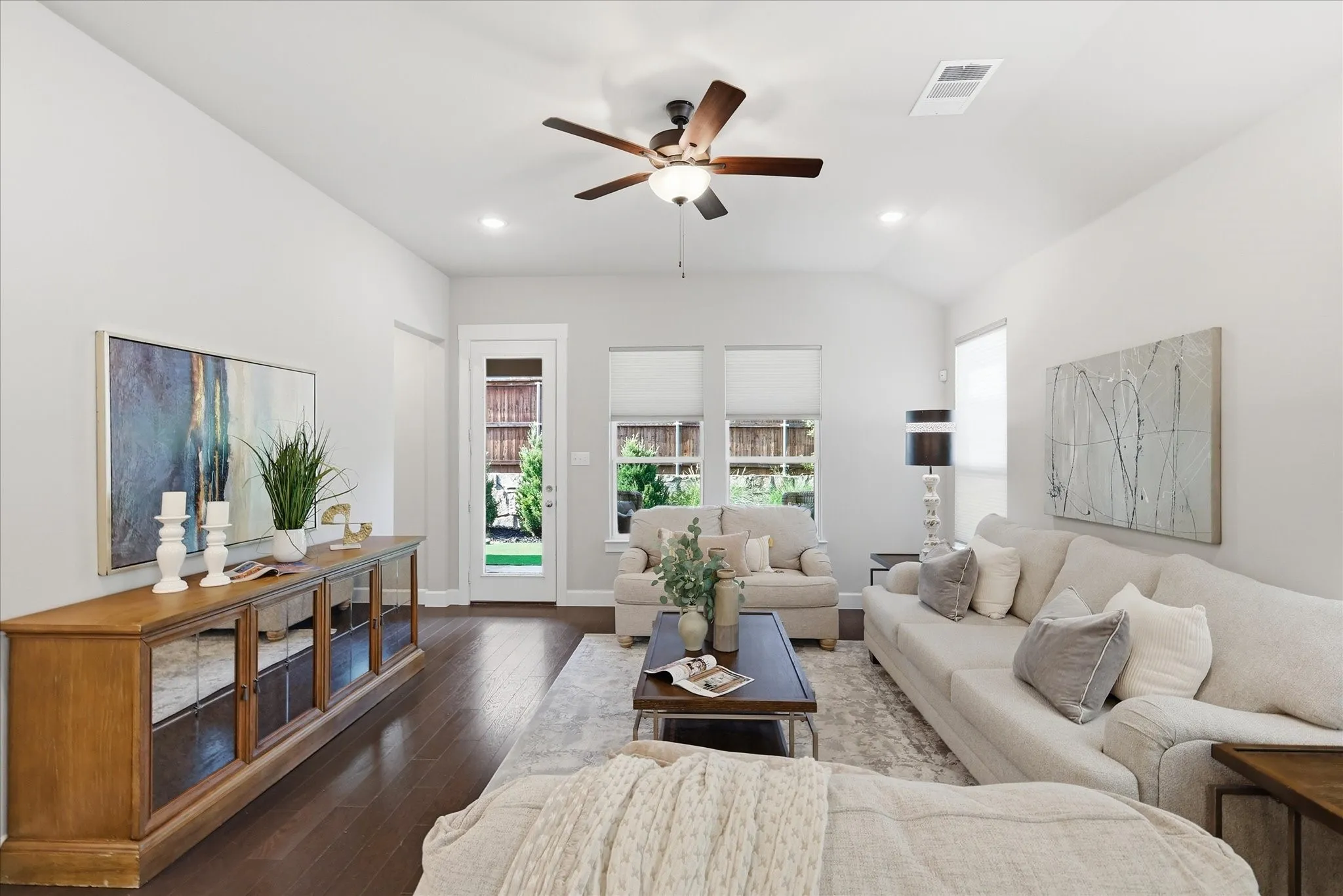 Vaulted ceiling with recessed lighting, wood-finish flooring, ceiling fan with integrated lighting, glass-paneled exterior door, and multiple windows