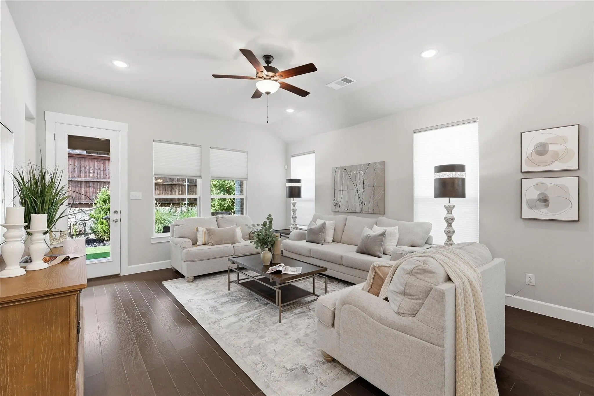 Vaulted ceiling with a ceiling fan, recessed lighting, wood-finish flooring, multiple windows, and a glass-paneled door