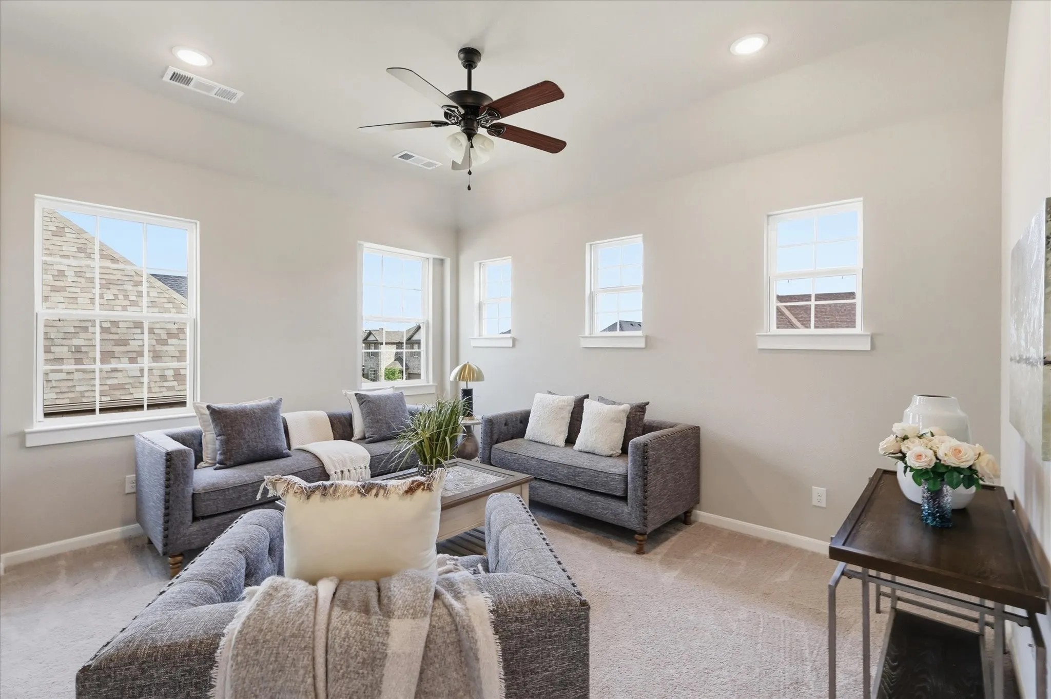 Vaulted ceiling with a ceiling fan, recessed lighting, multiple windows, and neutral carpeting