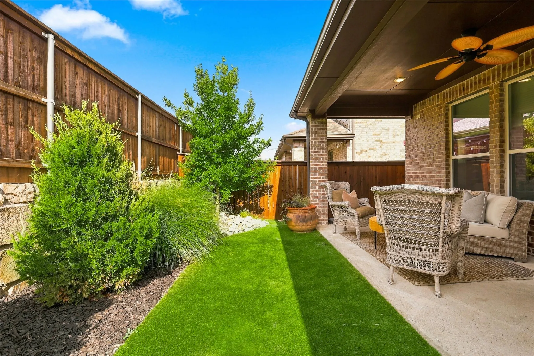 Private outdoor patio with a ceiling fan and recessed lighting, featuring a brick exterior, concrete flooring, and an adjacent lawn