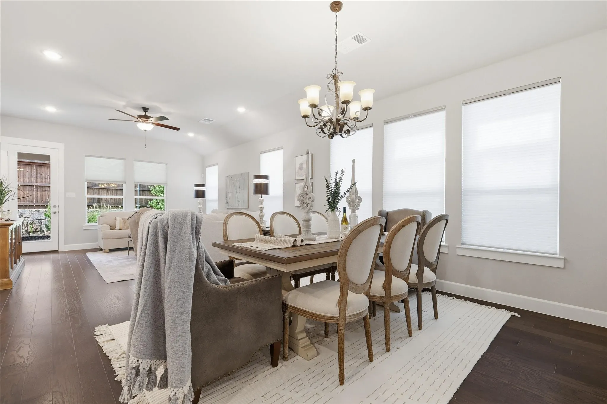 Open-concept living and dining areas featuring dark wood-finish flooring, recessed lighting, and a vaulted ceiling