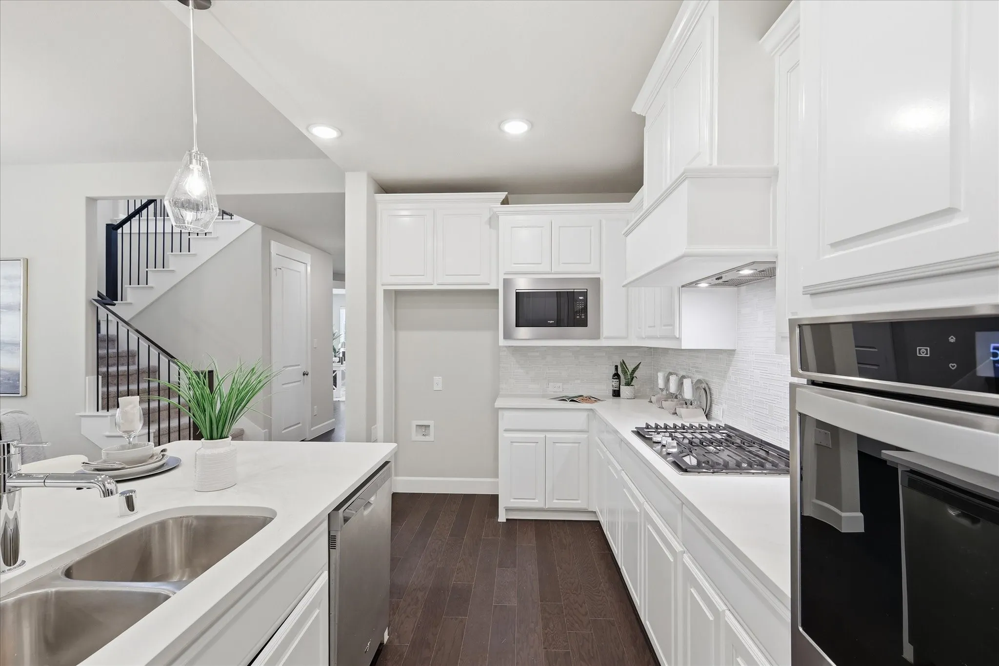 Kitchen featuring white cabinetry, stainless steel appliances, dark wood-finish flooring, and light countertops